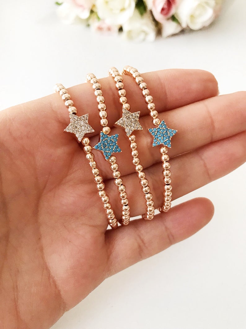 A dainty rose gold bracelet featuring a tiny star charm, adorned with either turquoise or zirconia beads, showcasing its delicate and adjustable design.