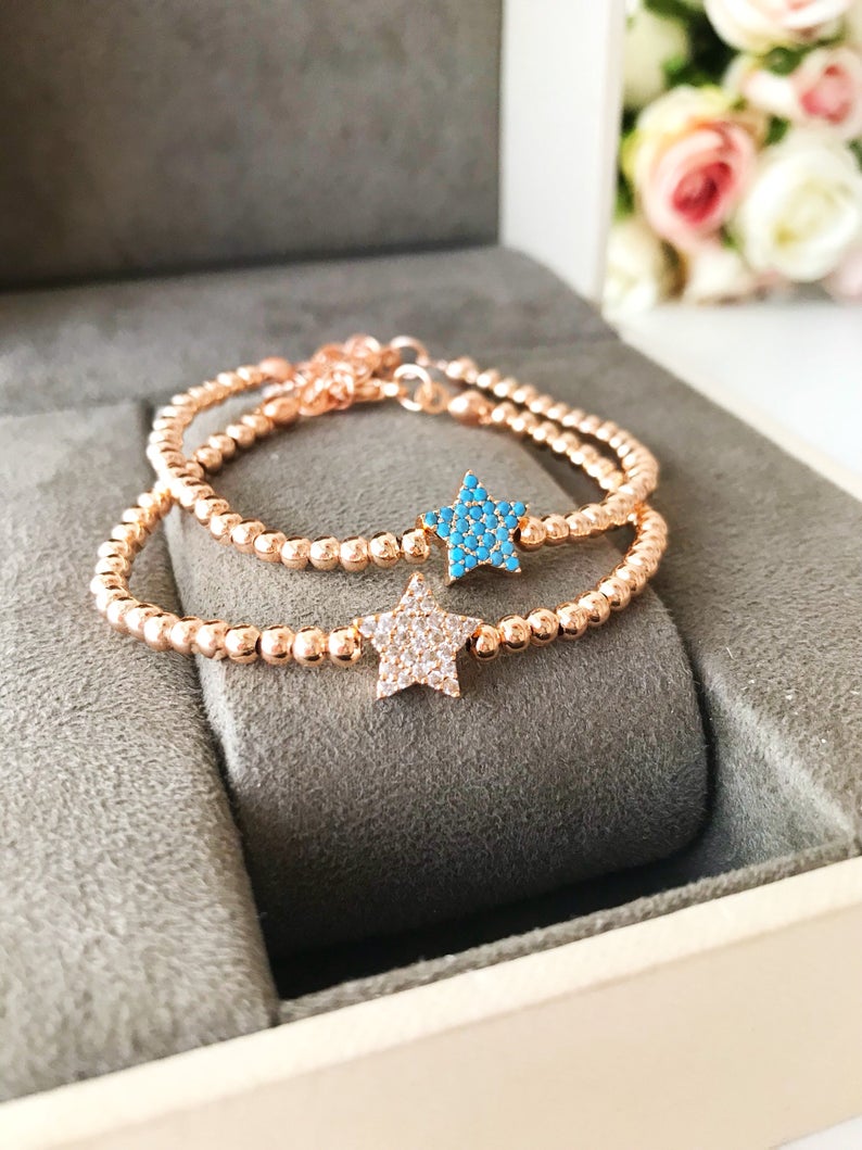 A dainty rose gold bracelet featuring a tiny star charm, adorned with either turquoise or zirconia beads, showcasing its delicate and adjustable design.