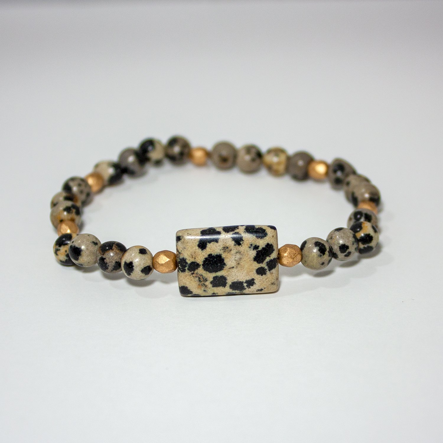 A stylish Dalmatian Jasper & Gold Beaded Stretch Bracelet featuring spotted jasper beads and gold plated brass accents, showcasing its unique design.