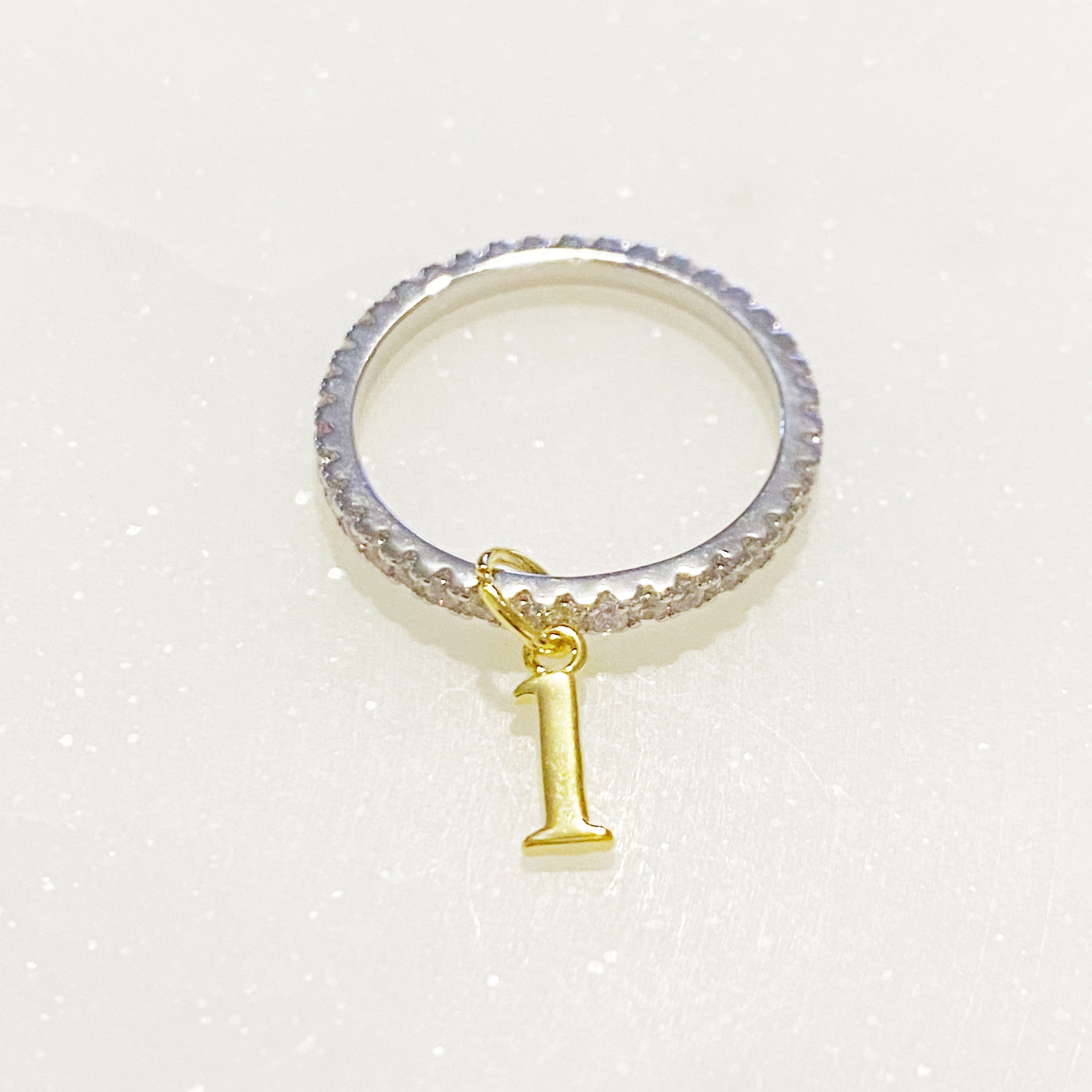 Dangle Initial Ring featuring a gold tone charm and sparkling cubic zirconia accents, elegantly designed for a dainty look.