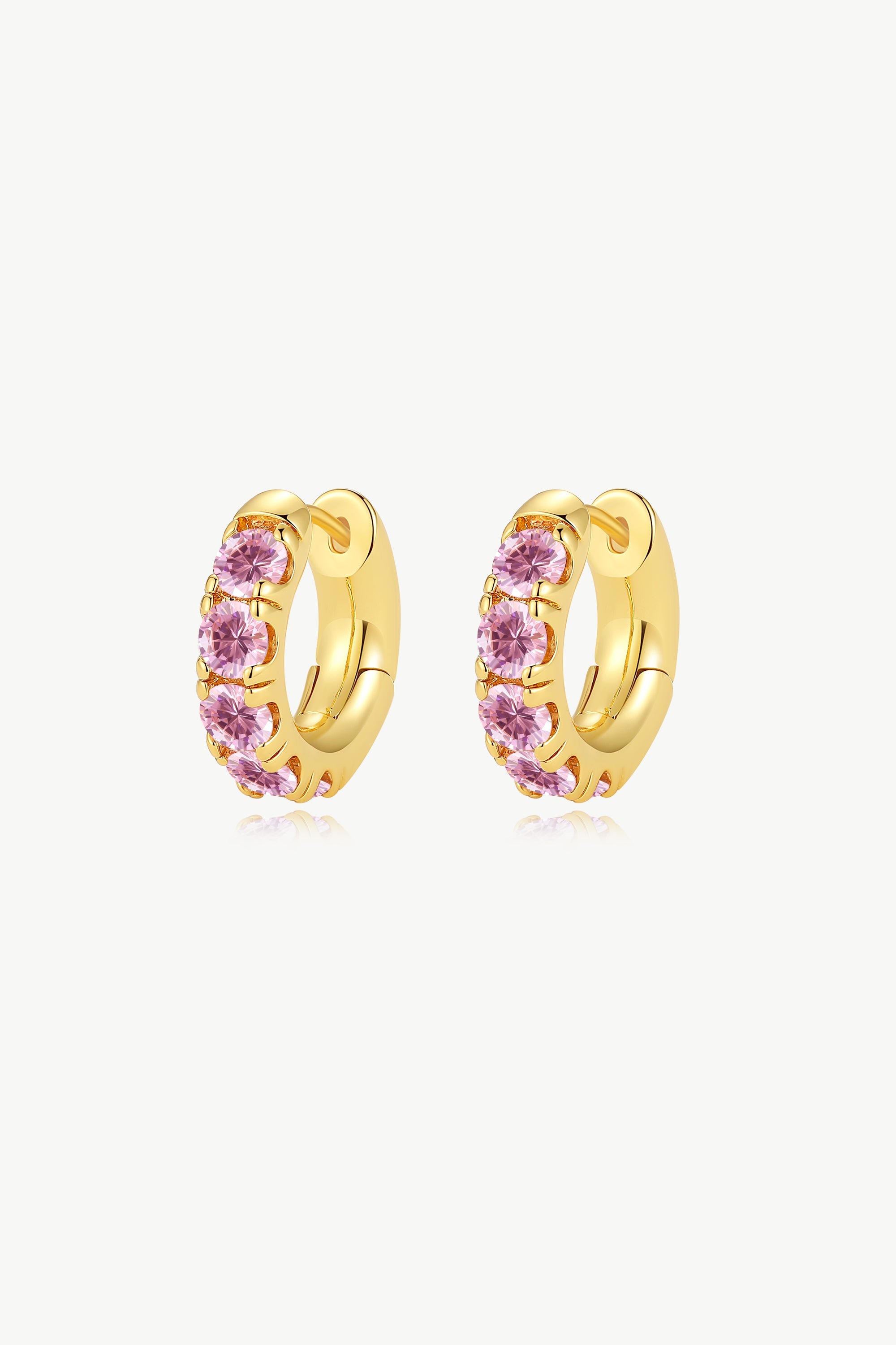 Daniela Gold Huggie Hoop Earrings featuring pink zirconia stones, elegantly designed for pierced ears.