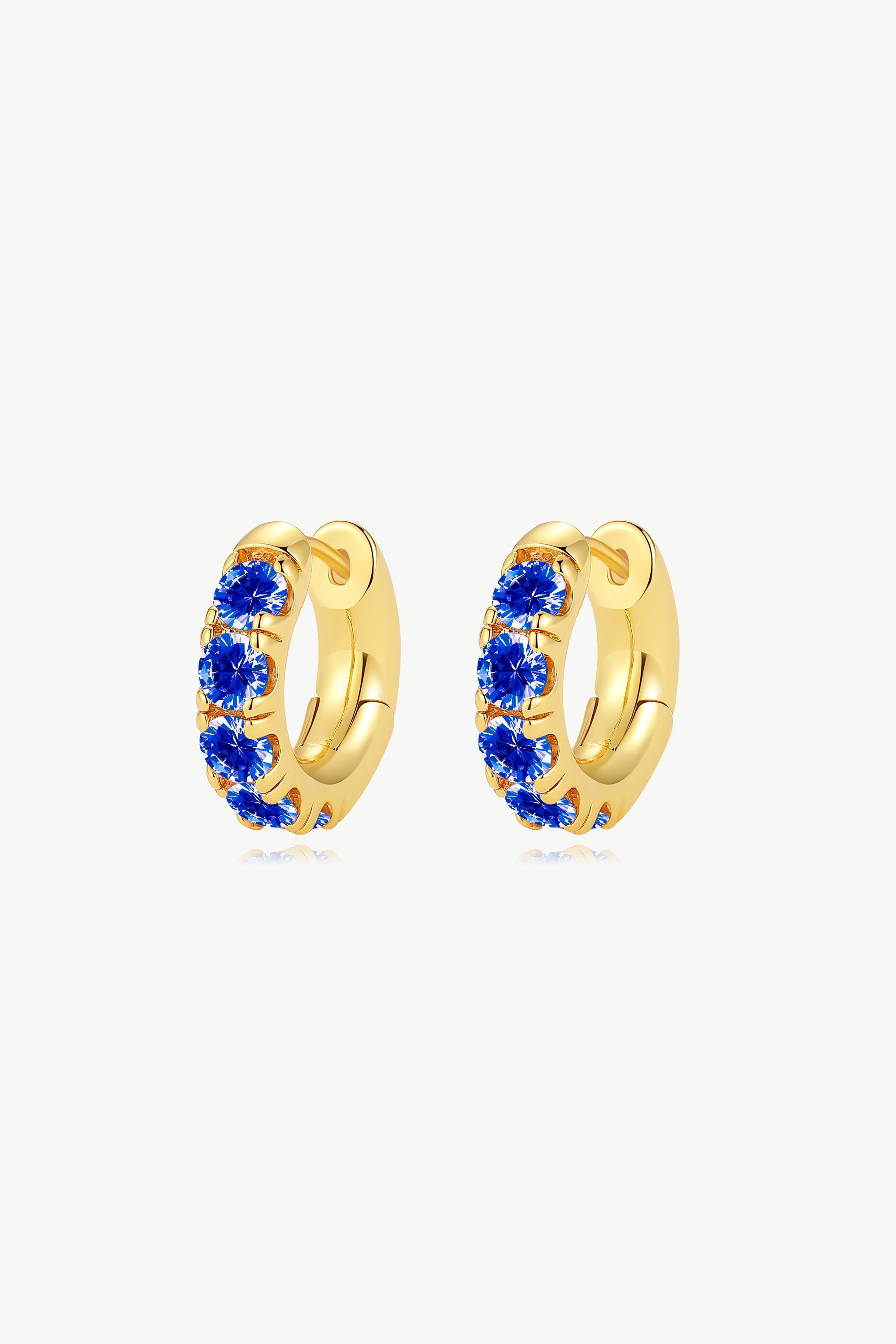 Daniela Gold Huggie Hoop Earrings featuring sapphire blue zirconia stones in a pavé-set design, perfect for stacking.