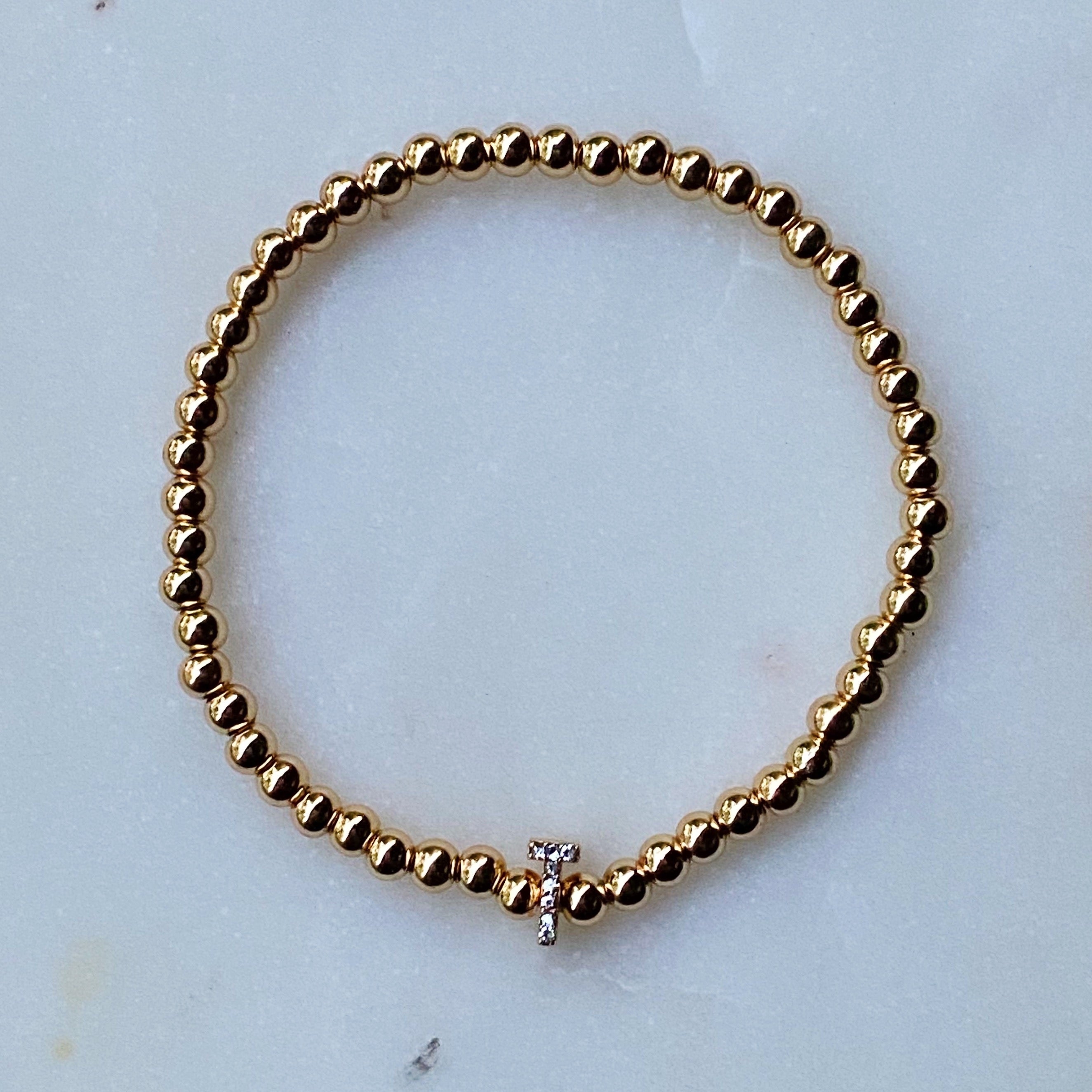 Darcy Initial Bracelet featuring gold tone ball beads and a sparkly initial accent, perfect for layering.