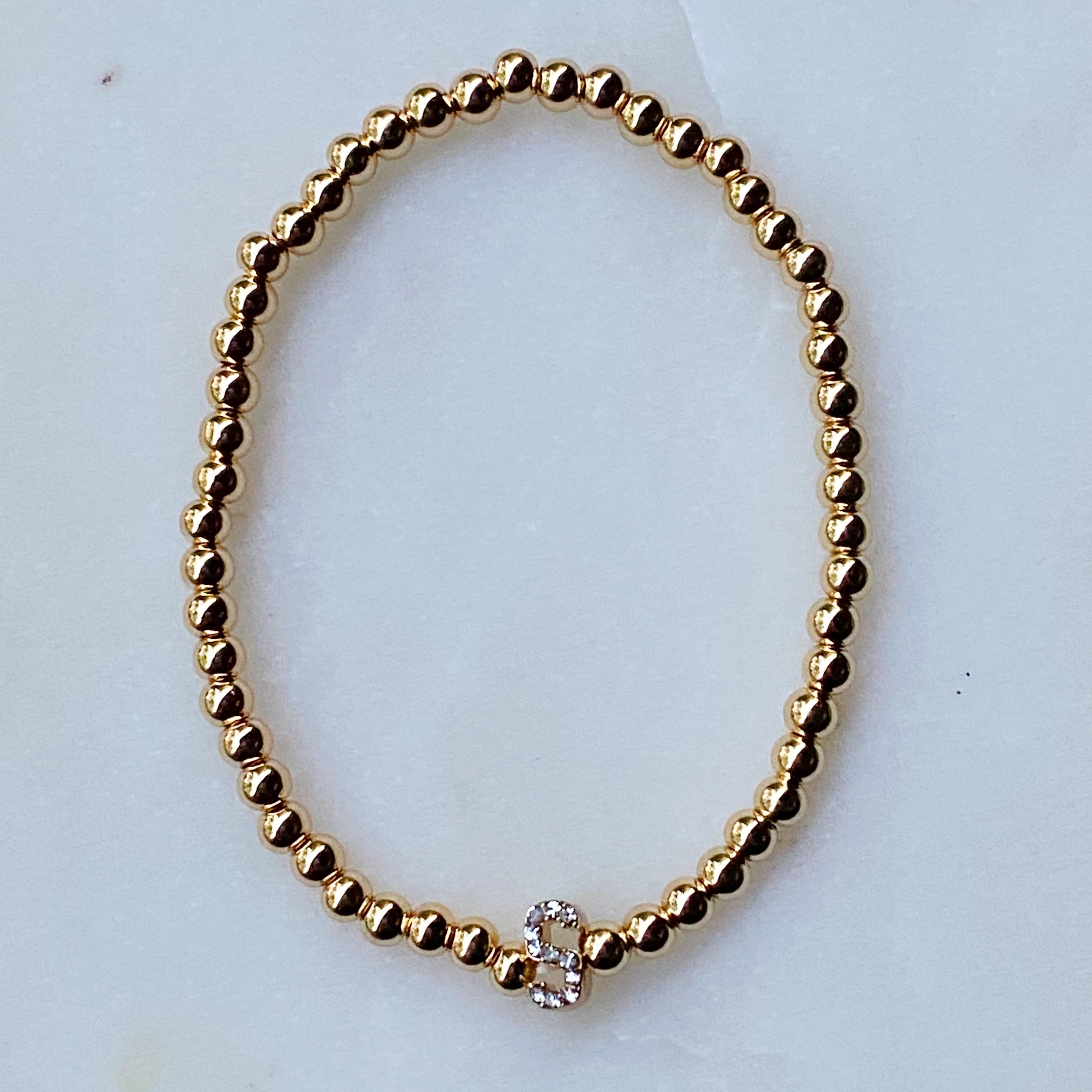 Darcy Initial Bracelet featuring gold tone ball beads and a sparkly initial accent, perfect for layering.