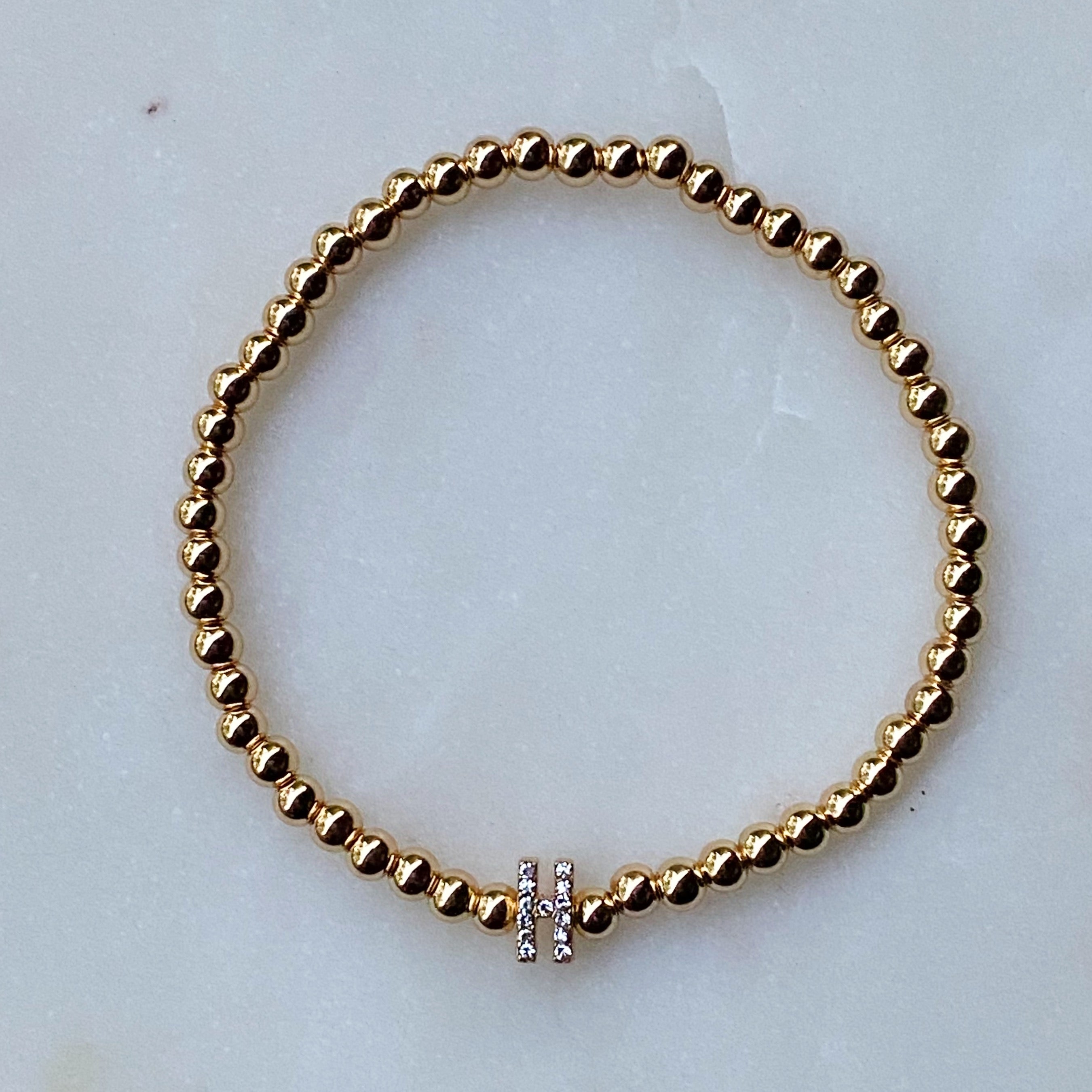 Darcy Initial Bracelet featuring gold tone ball beads and a sparkly initial accent, perfect for layering.