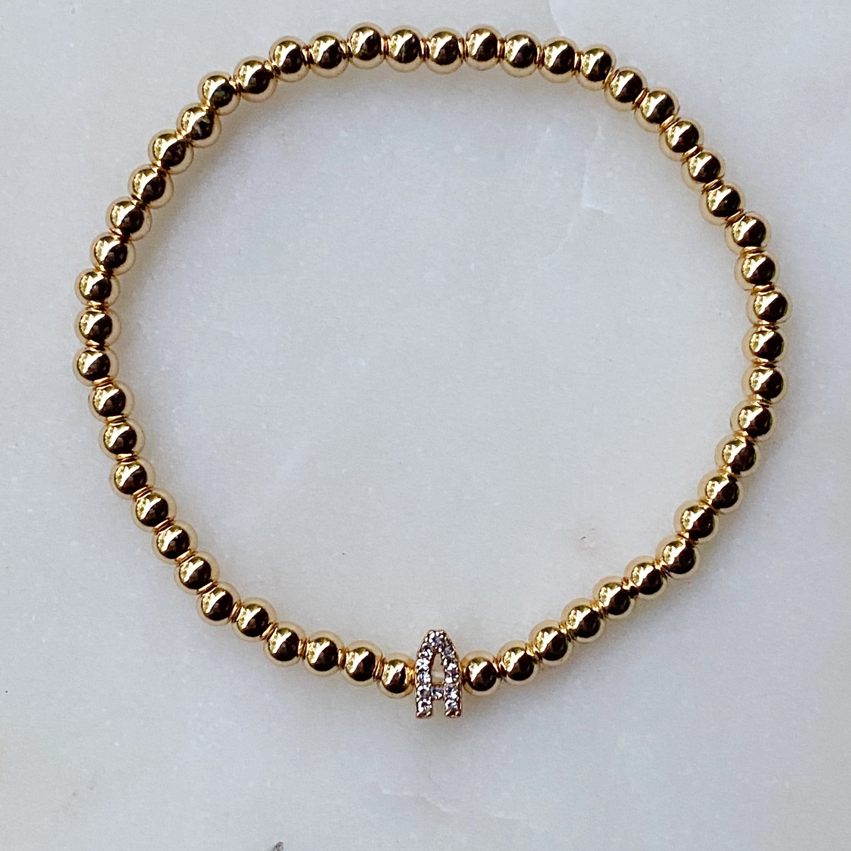 Darcy Initial Bracelet featuring gold tone ball beads and a sparkly initial accent, perfect for layering.