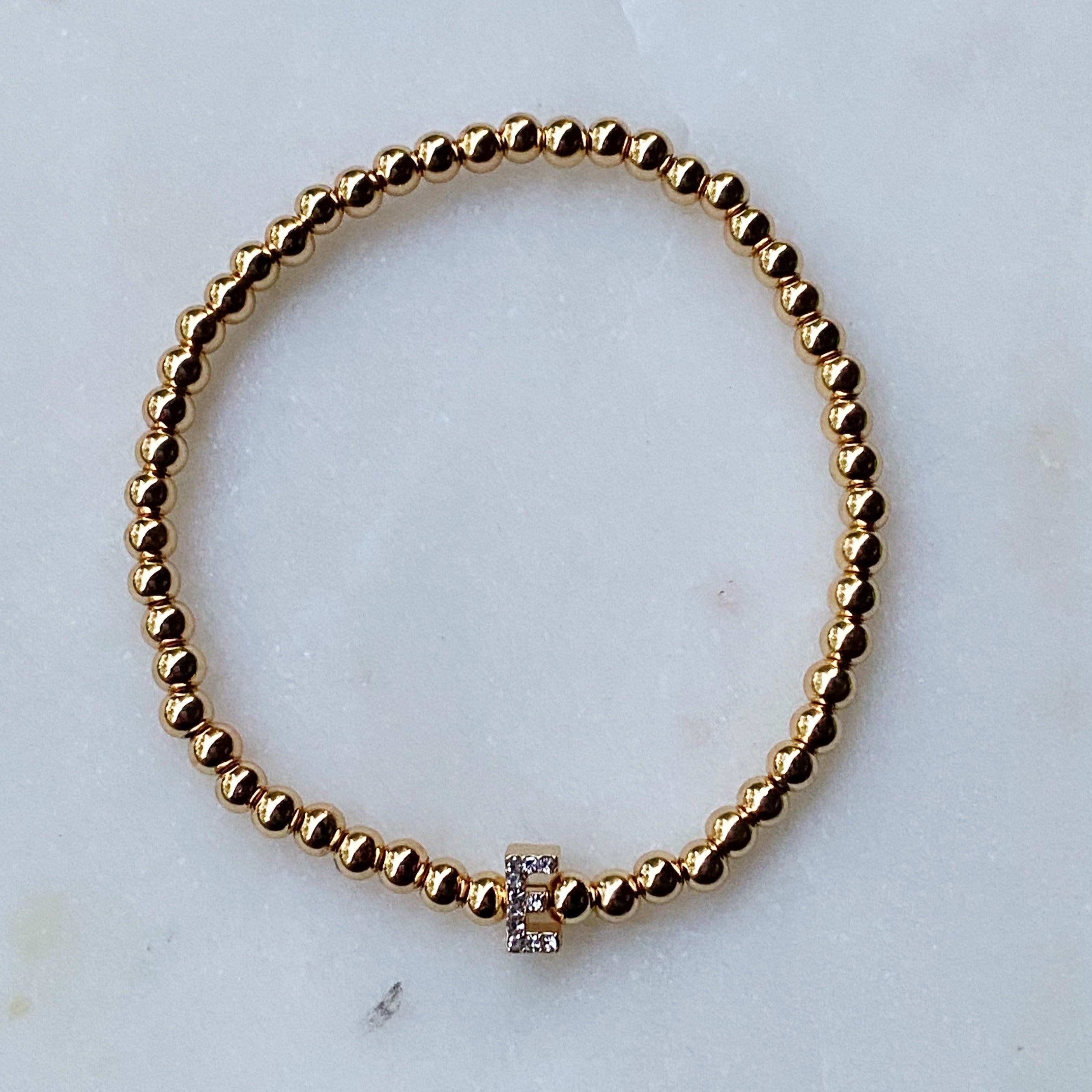 Darcy Initial Bracelet featuring gold tone ball beads and a sparkly initial accent, perfect for layering.