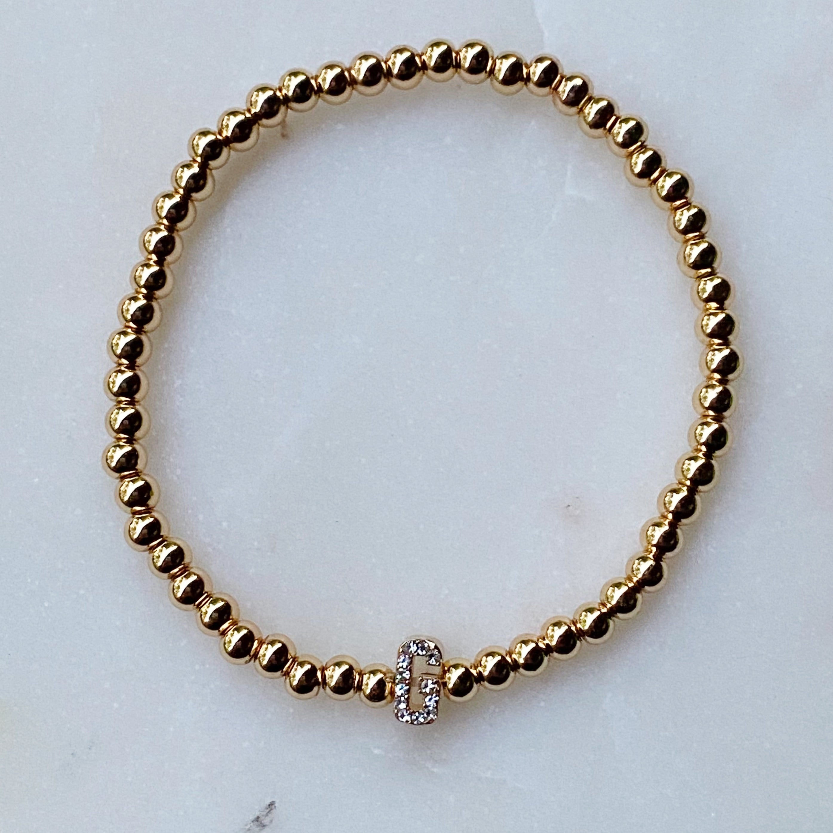 Darcy Initial Bracelet featuring gold tone ball beads and a sparkly initial accent, perfect for layering.