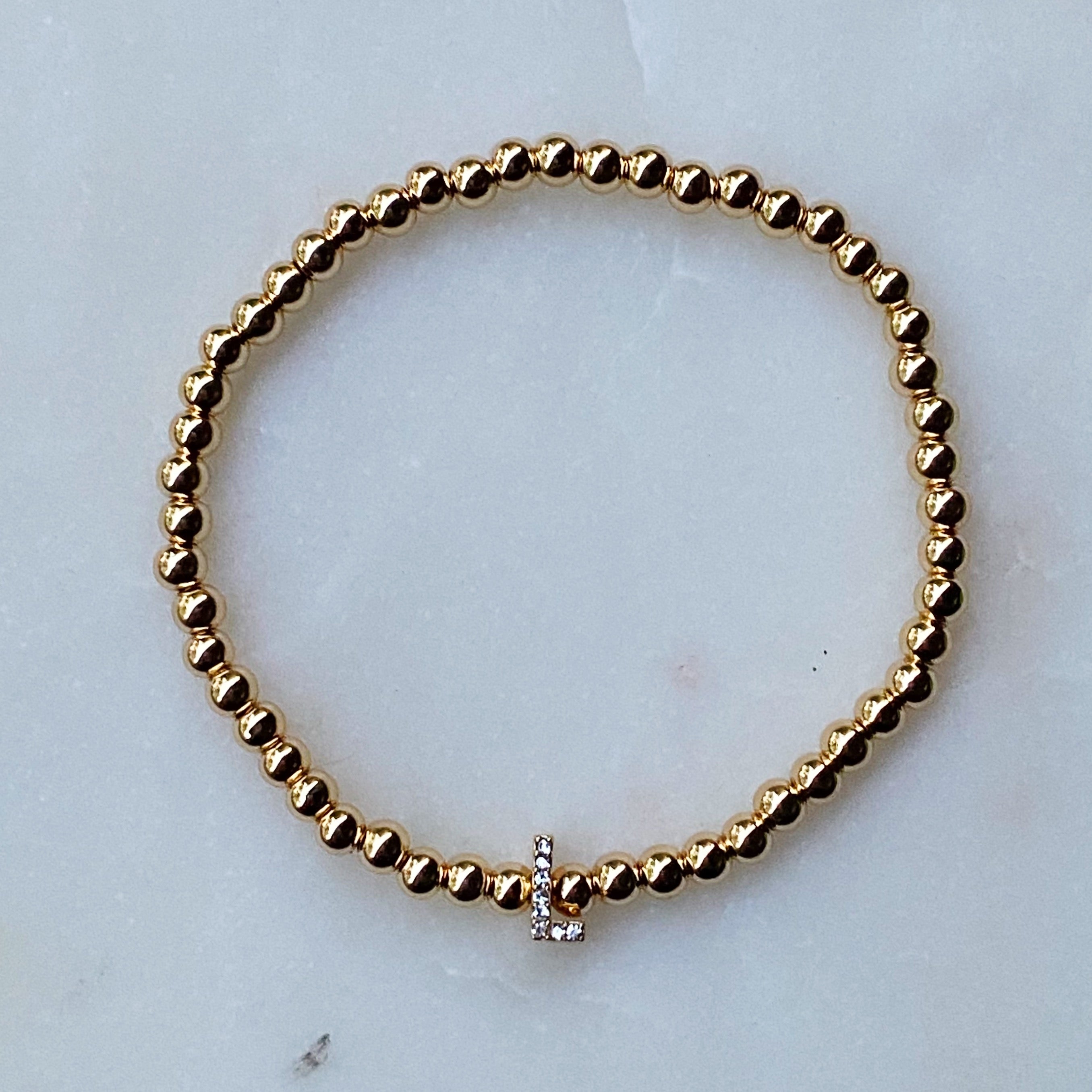 Darcy Initial Bracelet featuring gold tone ball beads and a sparkly initial accent, perfect for layering.