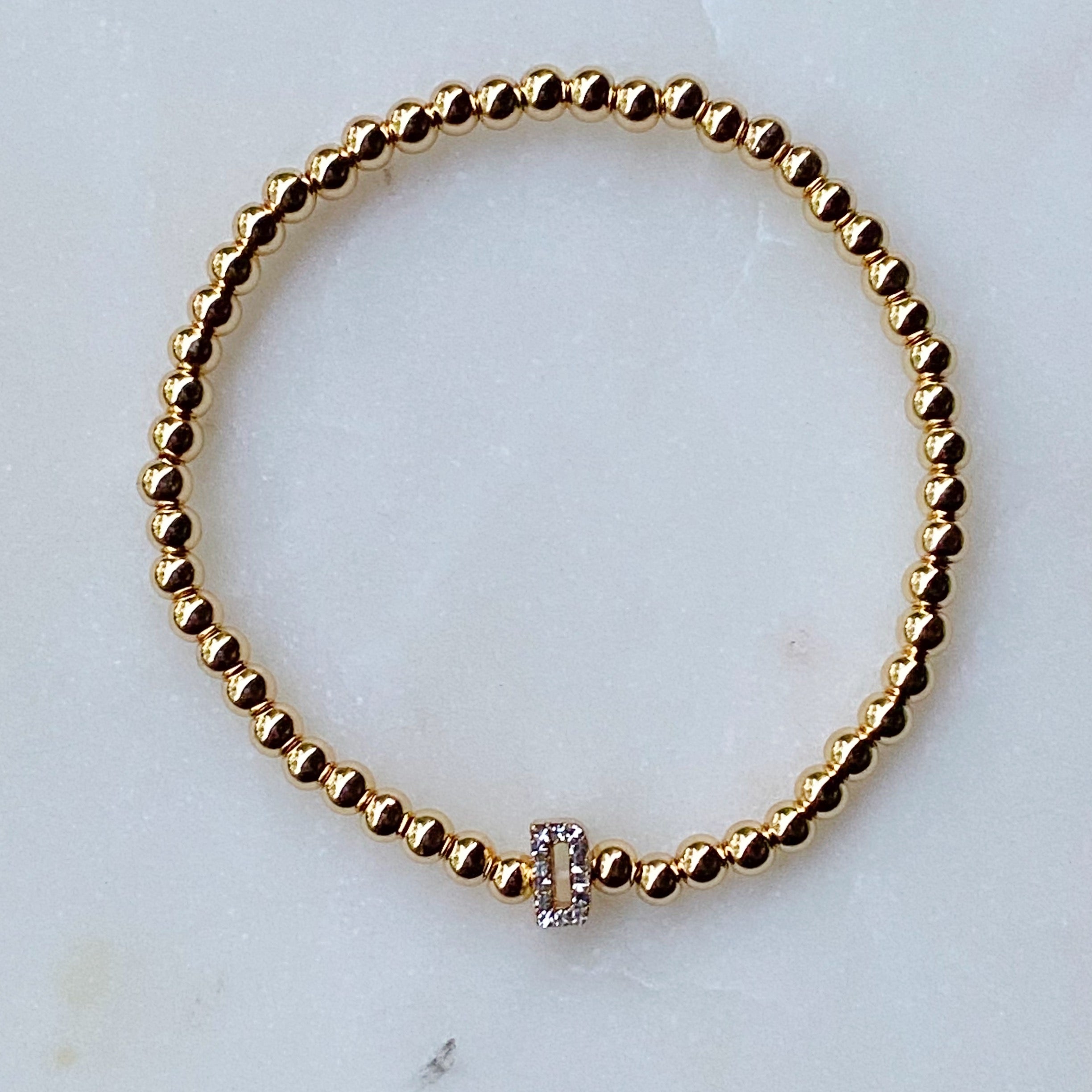 Darcy Initial Bracelet featuring gold tone ball beads and a sparkly initial accent, perfect for layering.