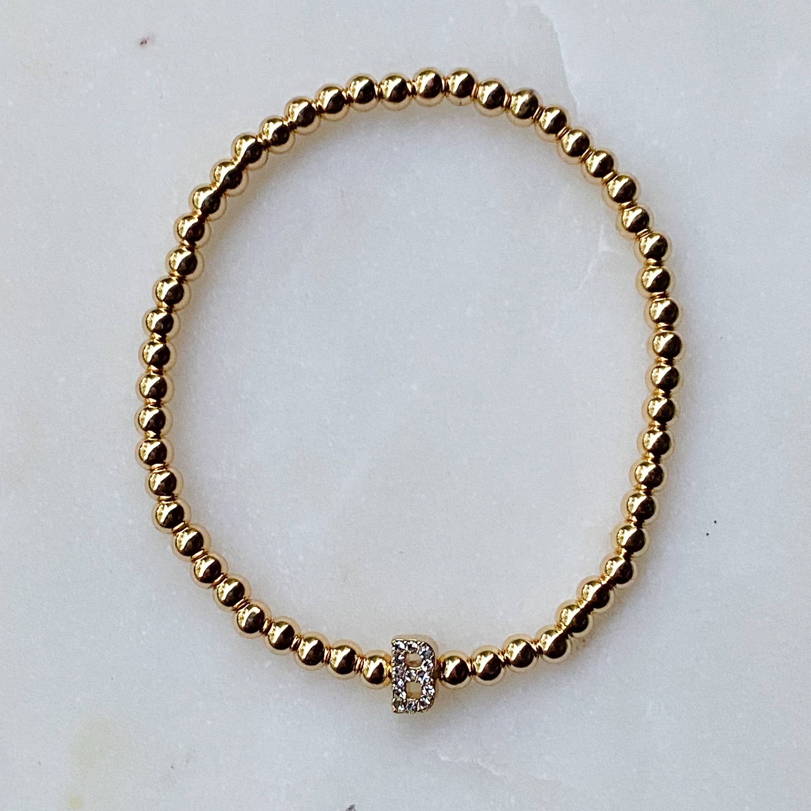 Darcy Initial Bracelet featuring gold tone ball beads and a sparkly initial accent, perfect for layering.