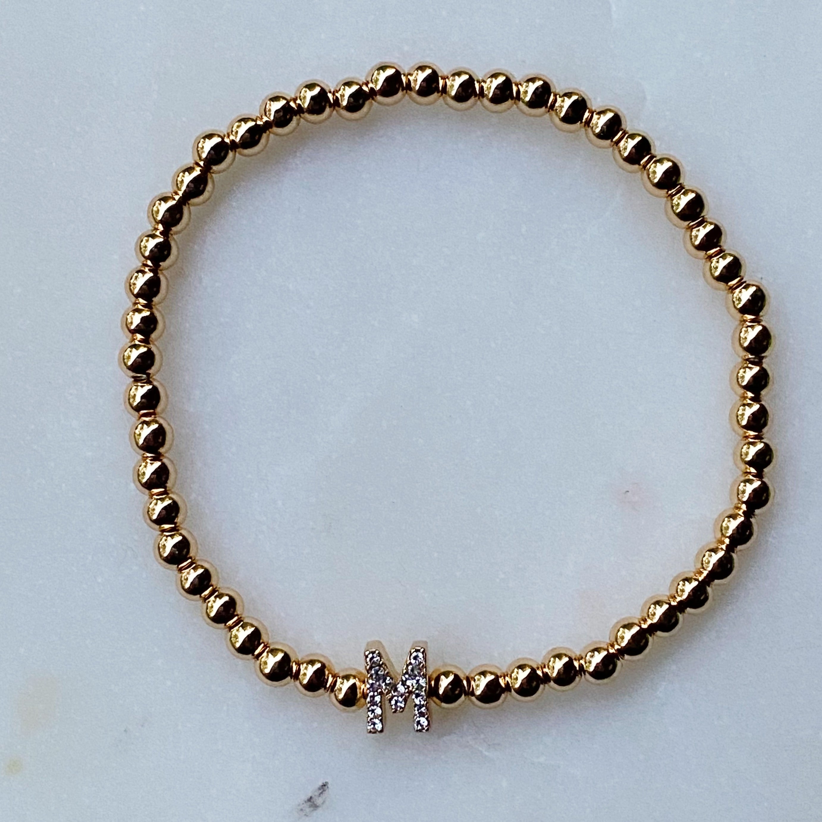 Darcy Initial Bracelet featuring gold tone ball beads and a sparkly initial accent, perfect for layering.