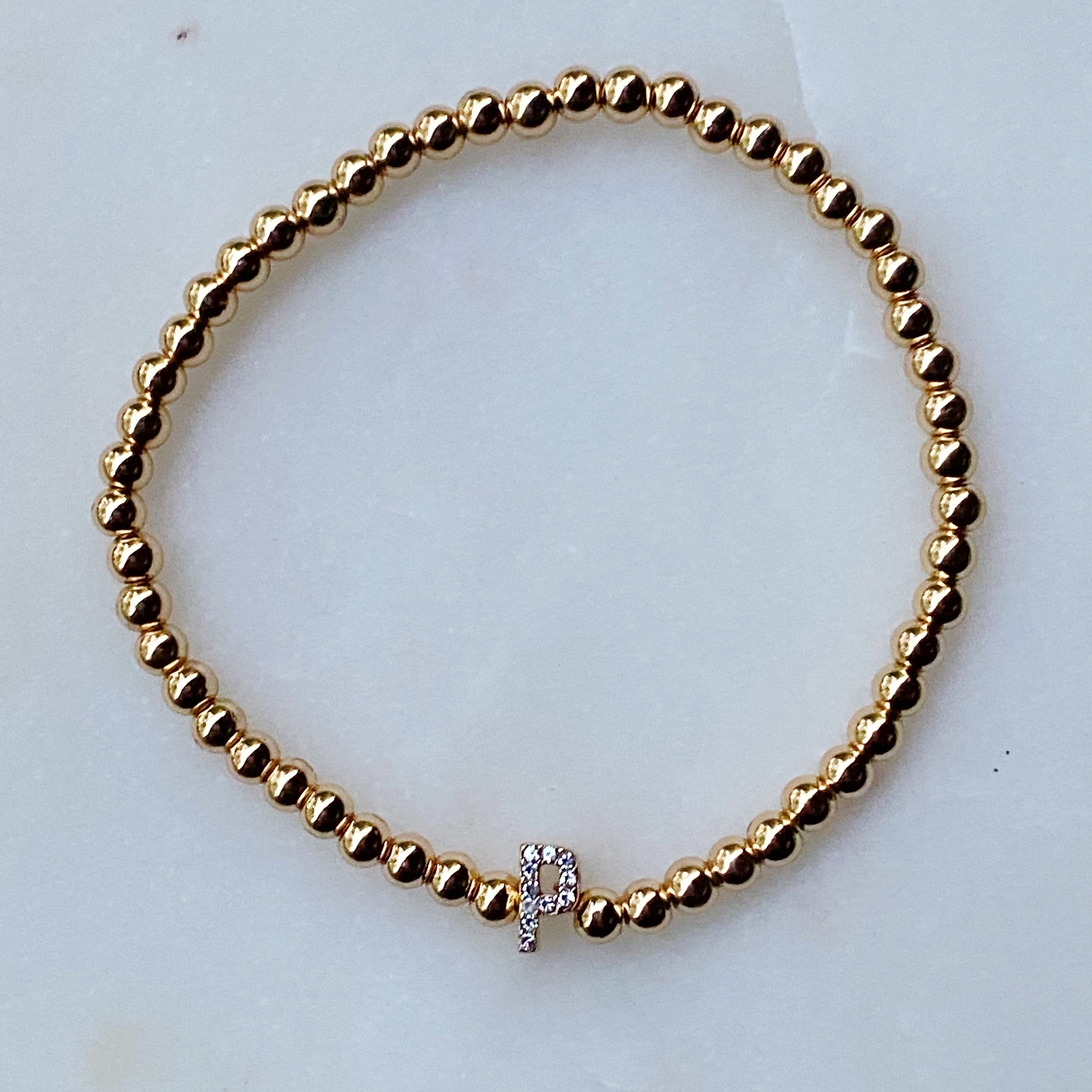 Darcy Initial Bracelet featuring gold tone ball beads and a sparkly initial accent, perfect for layering.