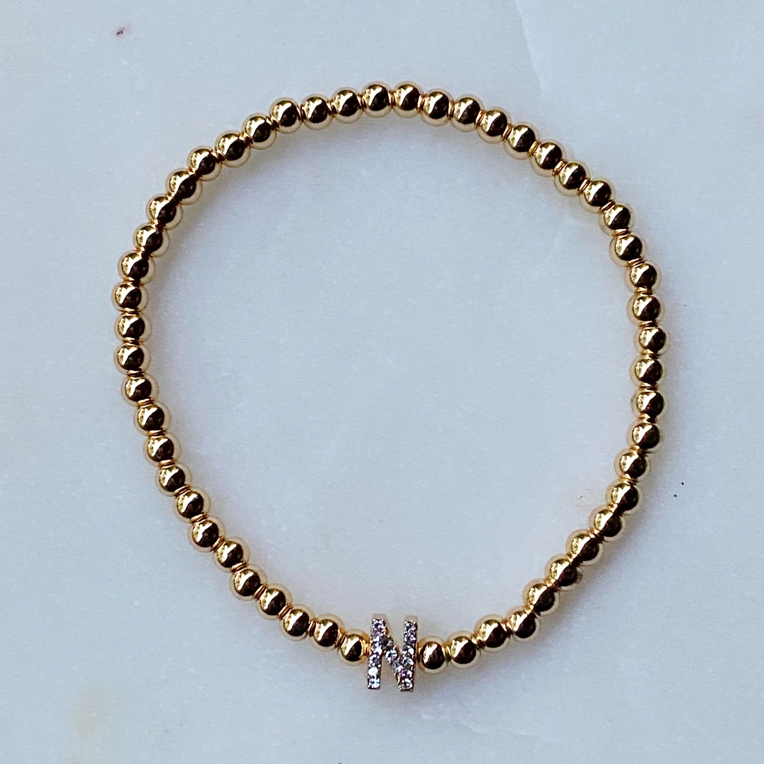 Darcy Initial Bracelet featuring gold tone ball beads and a sparkly initial accent, perfect for layering.