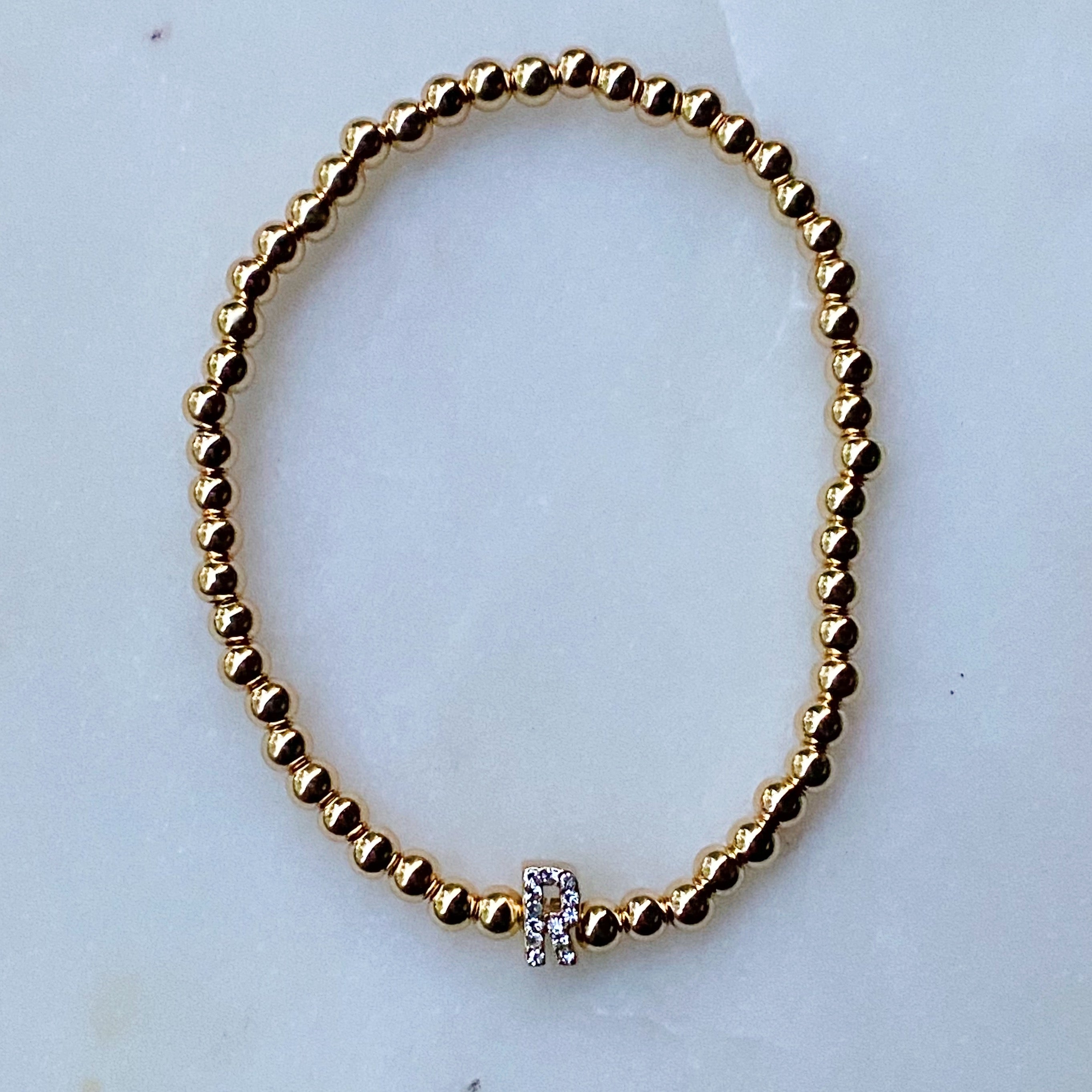 Darcy Initial Bracelet featuring gold tone ball beads and a sparkly initial accent, perfect for layering.