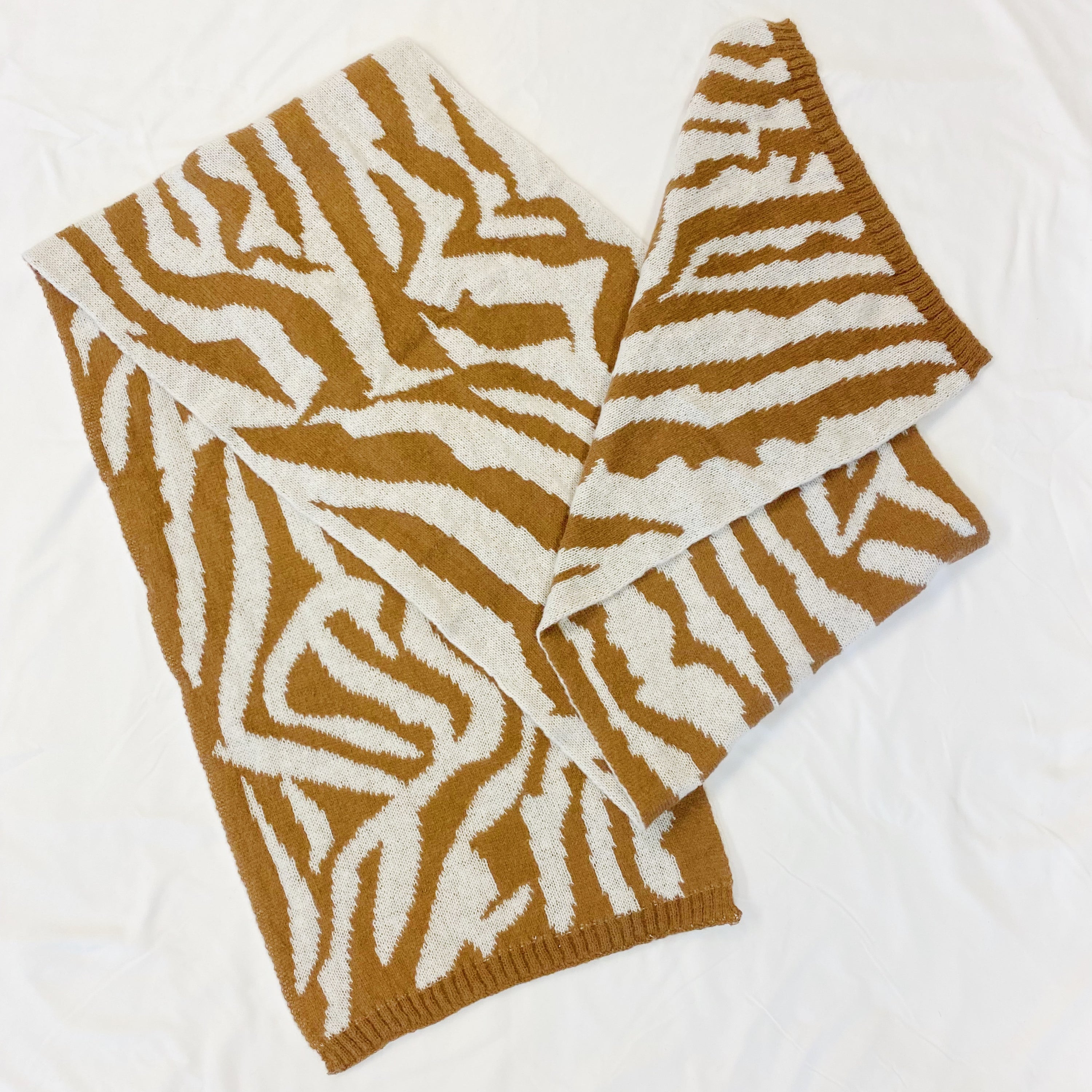 A cozy knit scarf featuring a trendy zebra pattern, reversible for versatile styling, measuring approximately 13 inches by 78 inches.