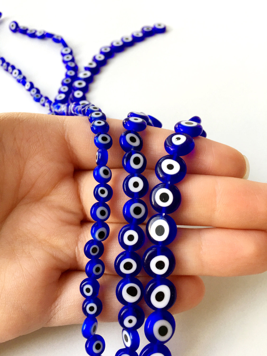 A collection of dark blue flat evil eye beads in various sizes, showcasing their unique handmade designs from Turkey.