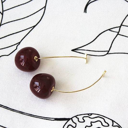 A pair of vintage rockabilly style dark red cherry earrings, featuring large resin cherries and gold-coated bronze ear wires.