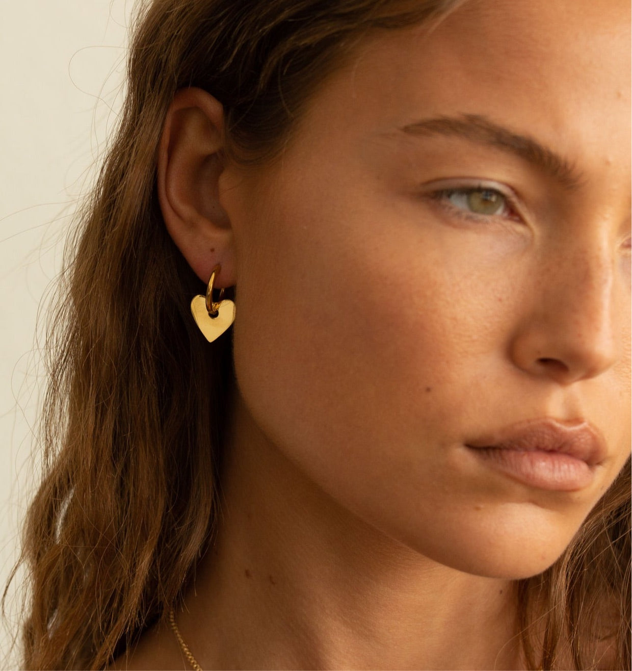 A pair of Dee Heart Earrings featuring a 2-in-1 hoop design with a heart charm, elegantly crafted in 18k gold plated stainless steel.