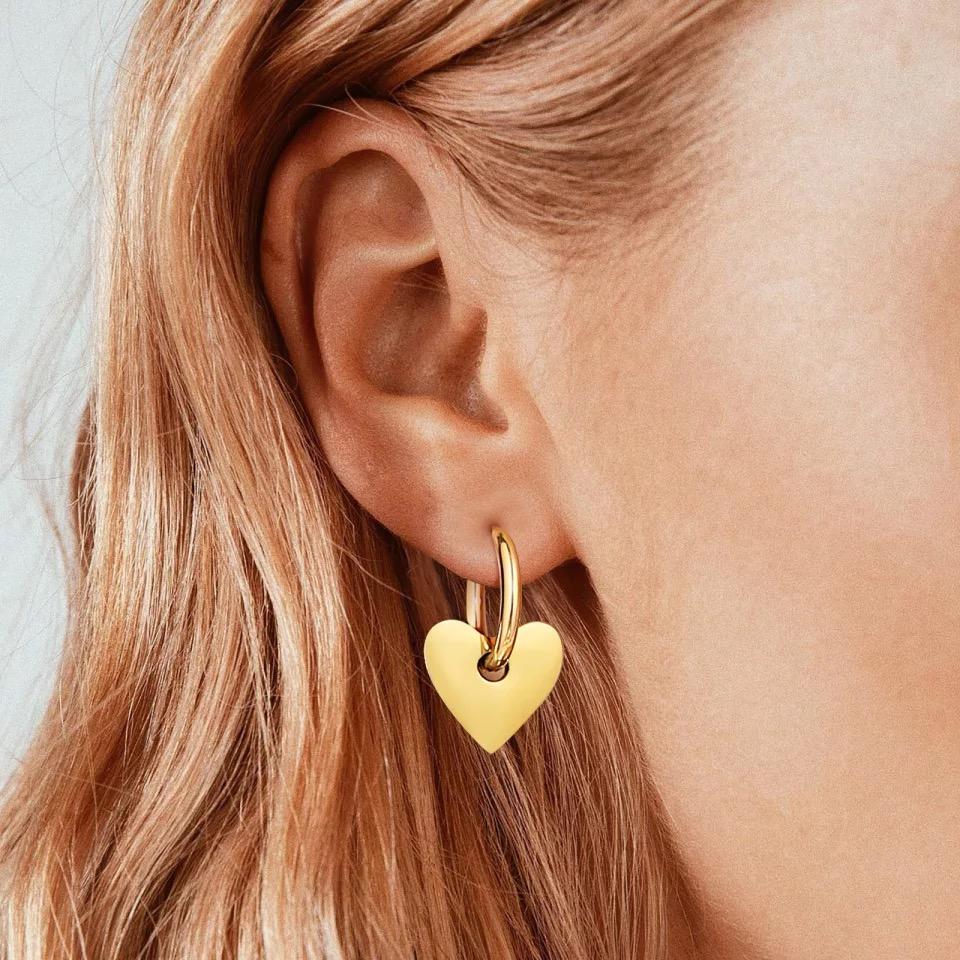 A pair of Dee Heart Earrings featuring a 2-in-1 hoop design with a heart charm, elegantly crafted in 18k gold plated stainless steel.