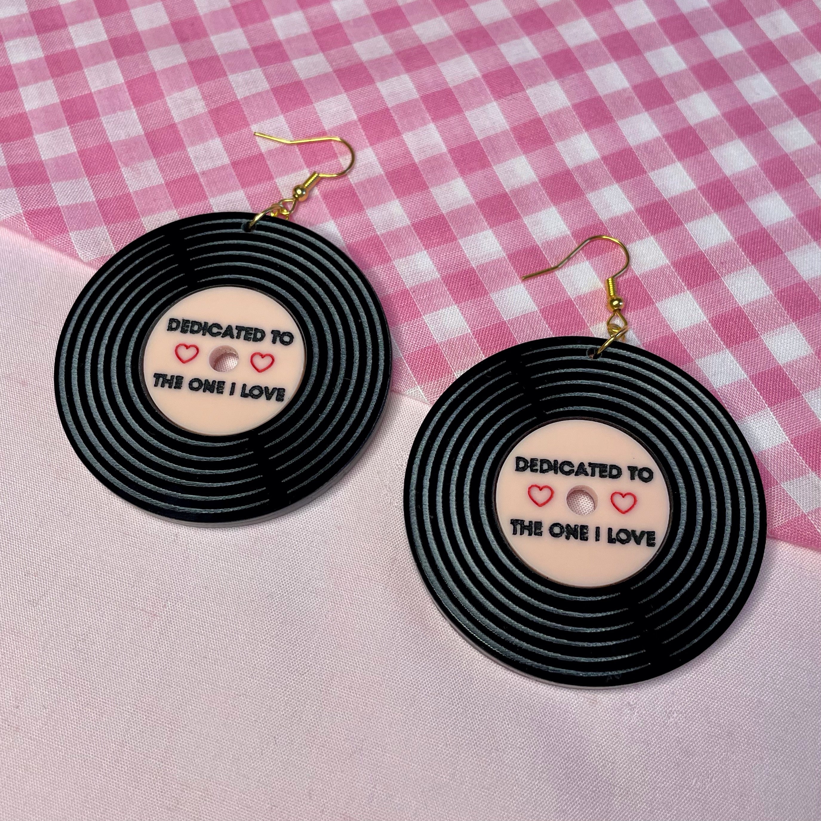 A pair of Dedicated Record Earrings featuring laser-cut black and baby pink acrylic in a vintage record design, measuring 5.2cm each.