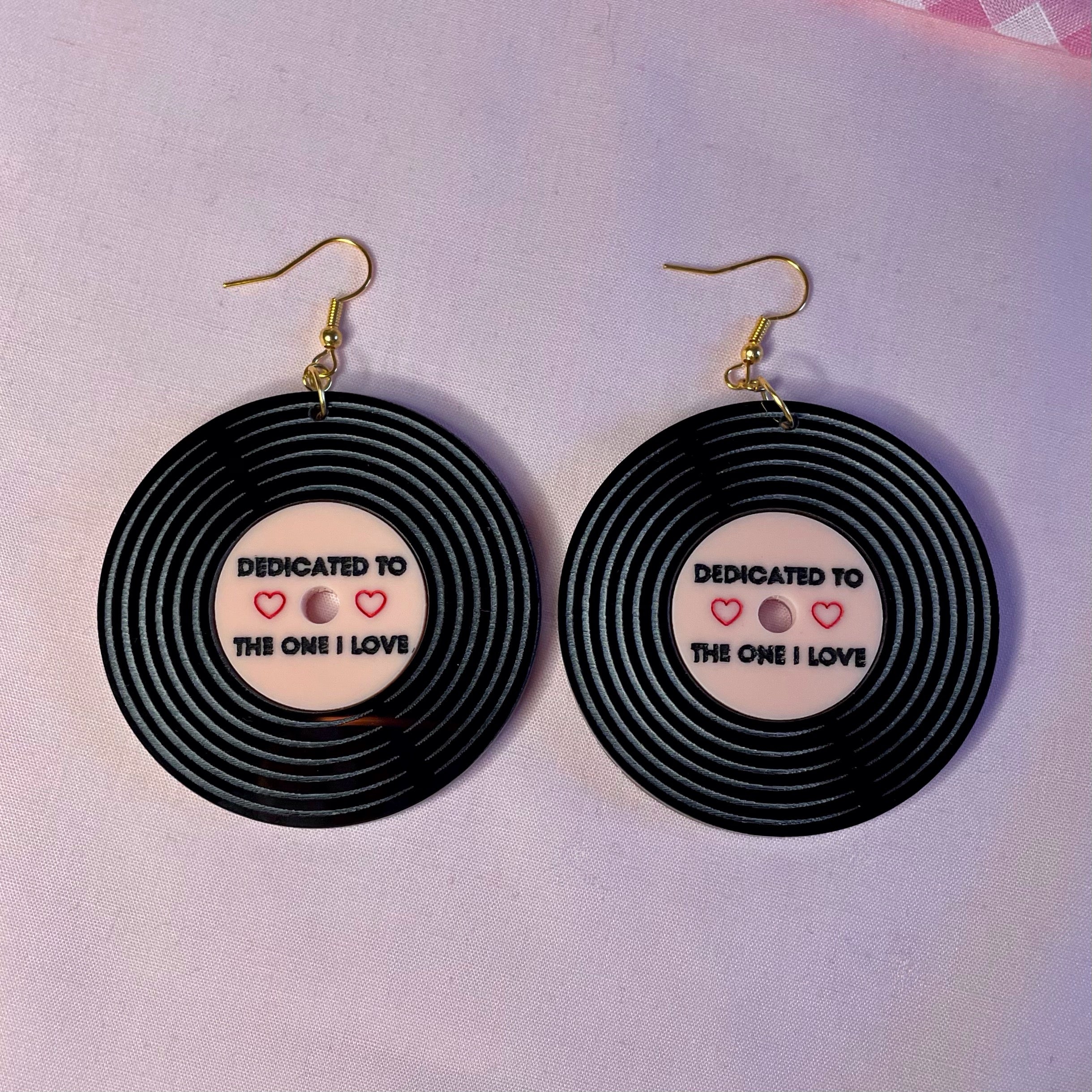 A pair of Dedicated Record Earrings featuring laser-cut black and baby pink acrylic in a vintage record design, measuring 5.2cm each.