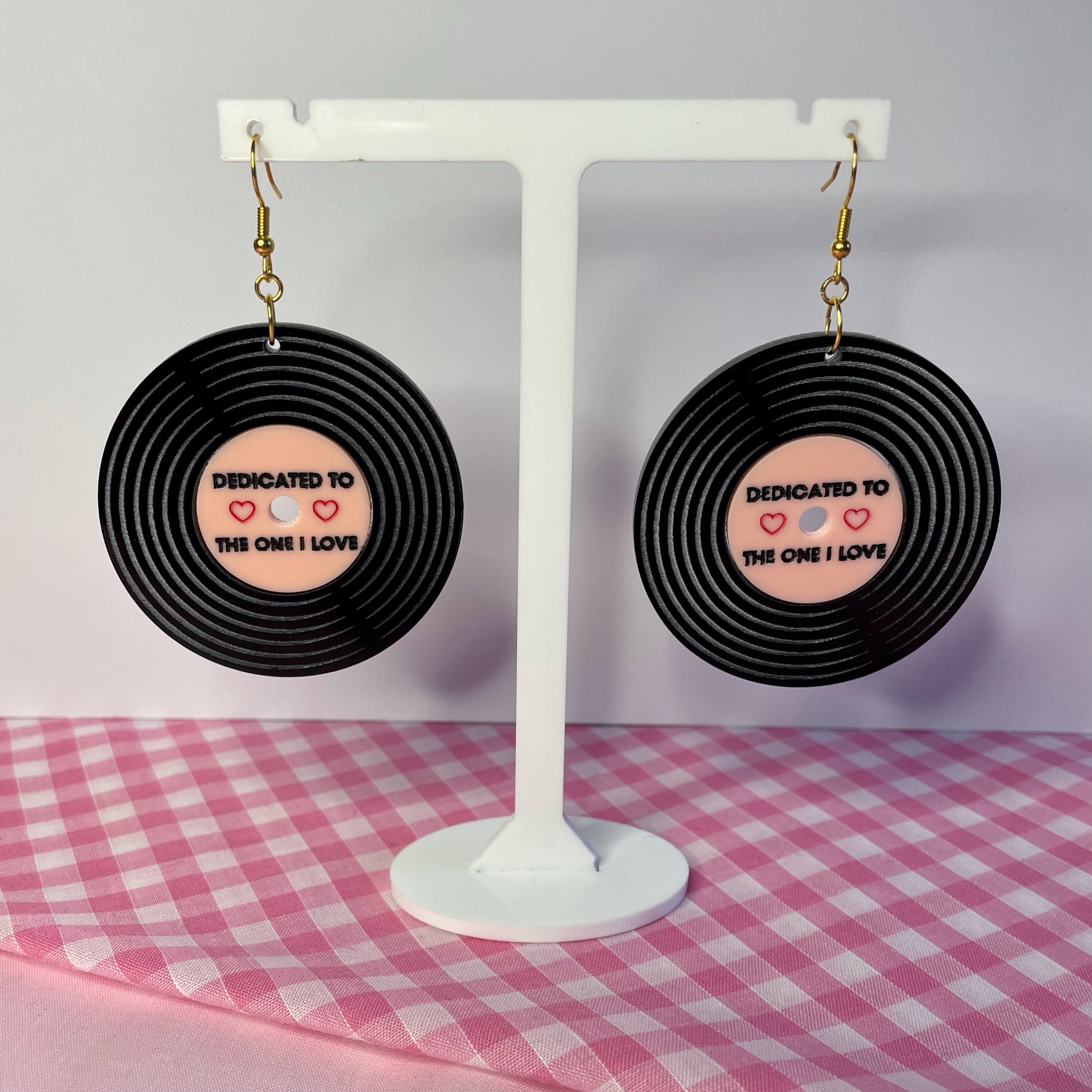 A pair of Dedicated Record Earrings featuring laser-cut black and baby pink acrylic in a vintage record design, measuring 5.2cm each.