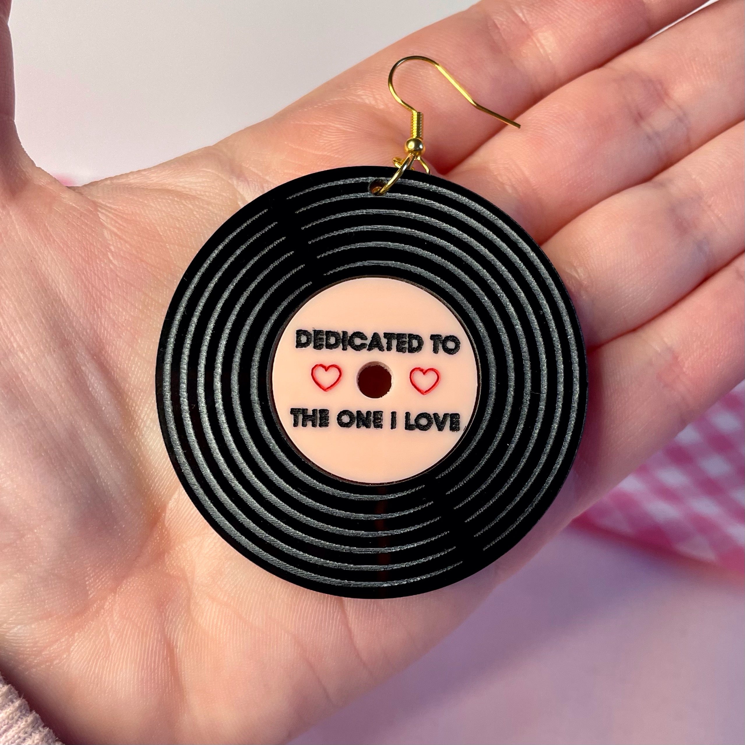 A pair of Dedicated Record Earrings featuring laser-cut black and baby pink acrylic in a vintage record design, measuring 5.2cm each.