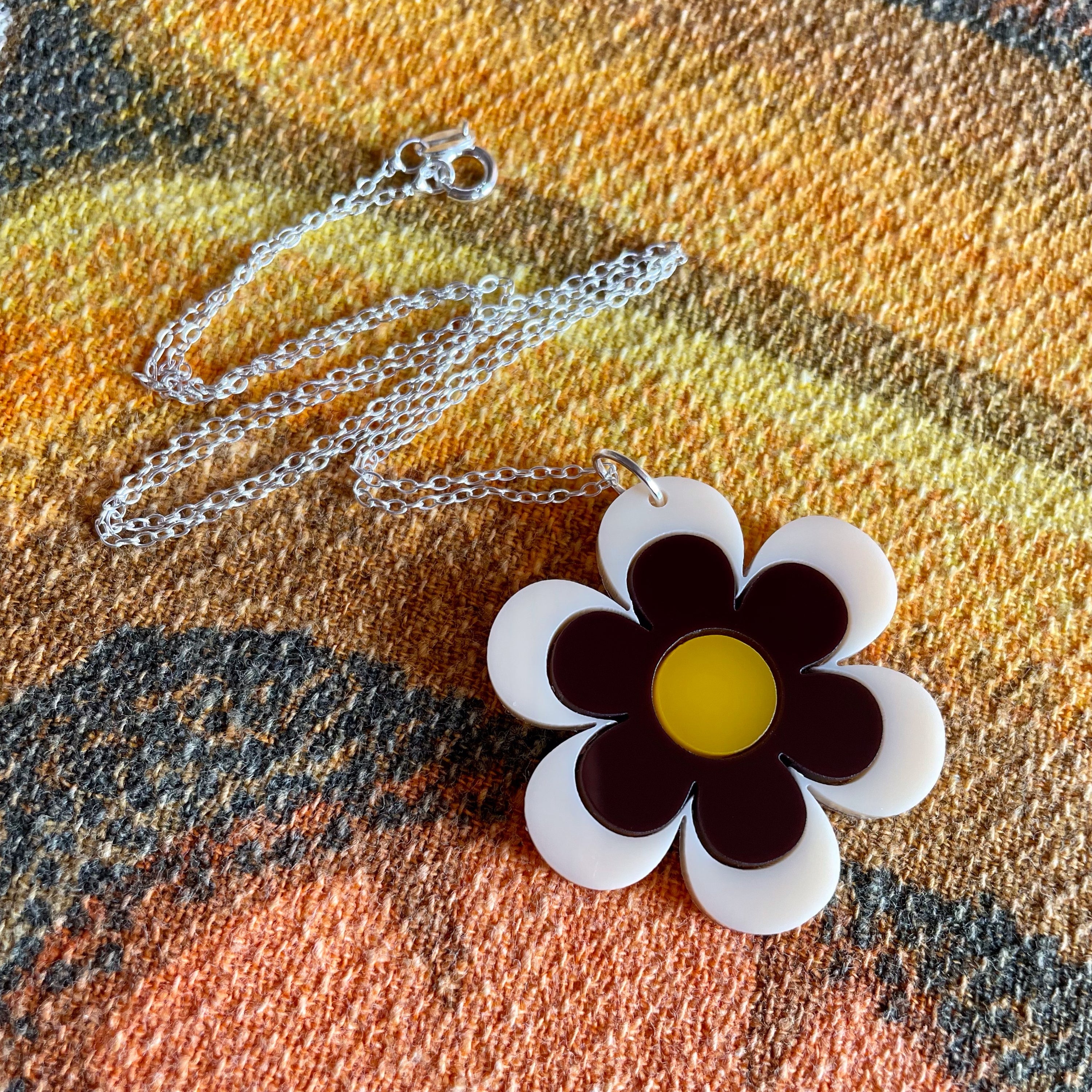 Delilah Daisy Necklace featuring retro design with laser-cut acrylic and sterling silver chain, showcasing a daisy motif.