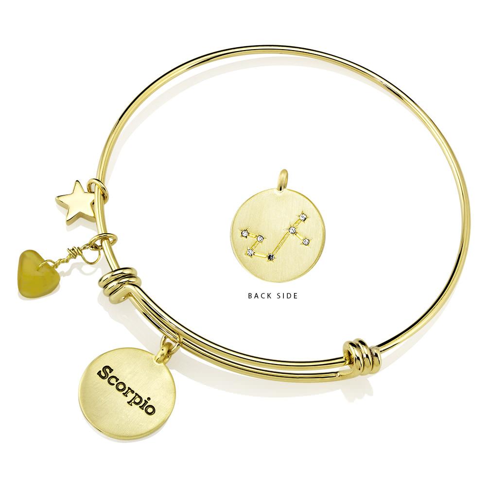 Elegant gold-plated bangle featuring zodiac charms and simulated diamonds, perfect for astrology lovers.