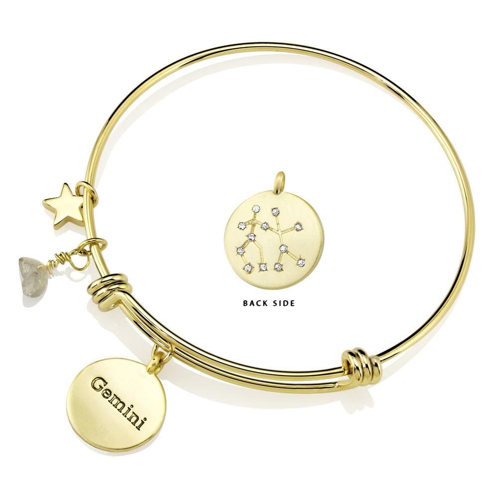 Elegant gold-plated bangle featuring zodiac charms and simulated diamonds, perfect for astrology lovers.