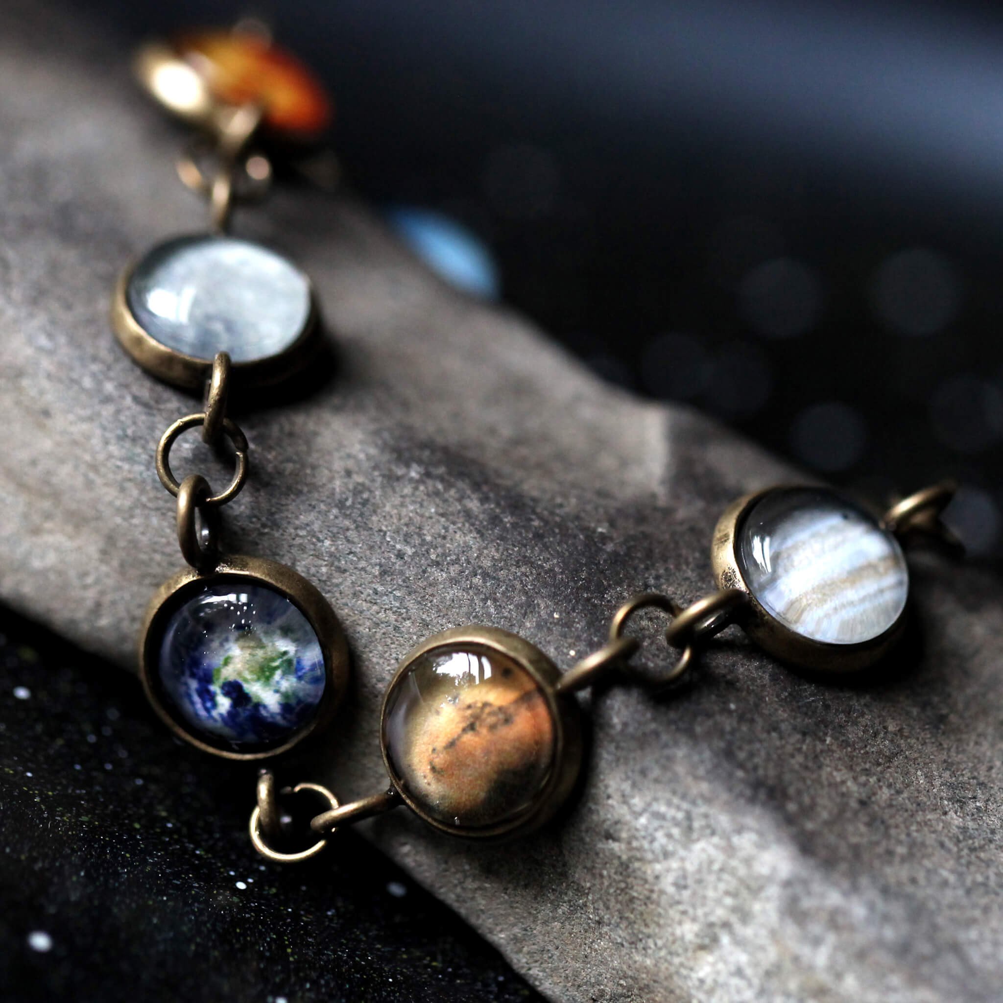 Solar System Galaxy Bracelet featuring planets in antique silver and bronze tones, handcrafted with plated brass and glass.