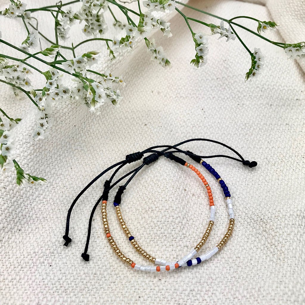 A vibrant set of two handmade Dori Beaded Bracelets featuring colorful glass beads on cotton thread, perfect for layering.