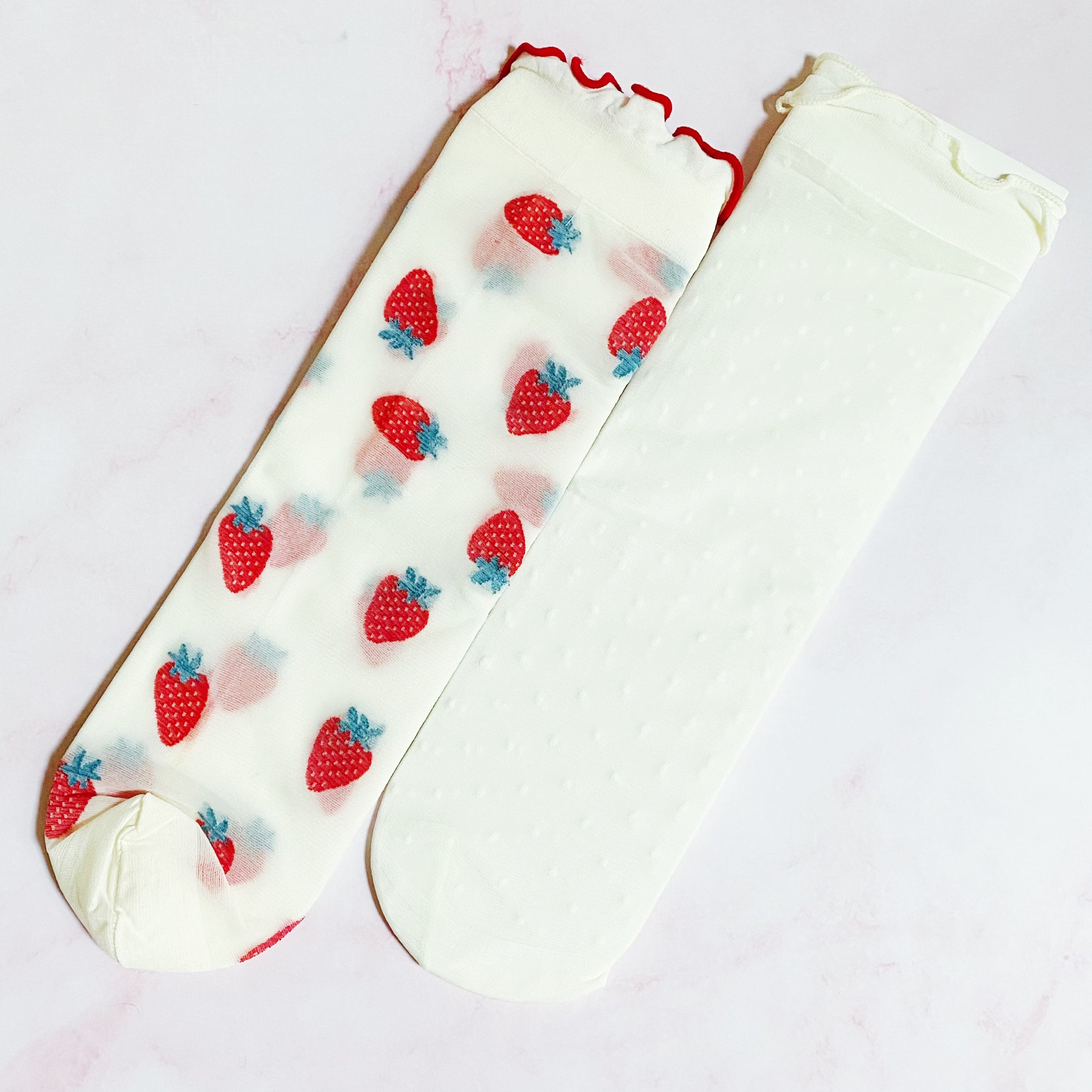 A set of two pairs of sheer socks featuring playful dots and strawberries, showcasing their soft and stretchy material.