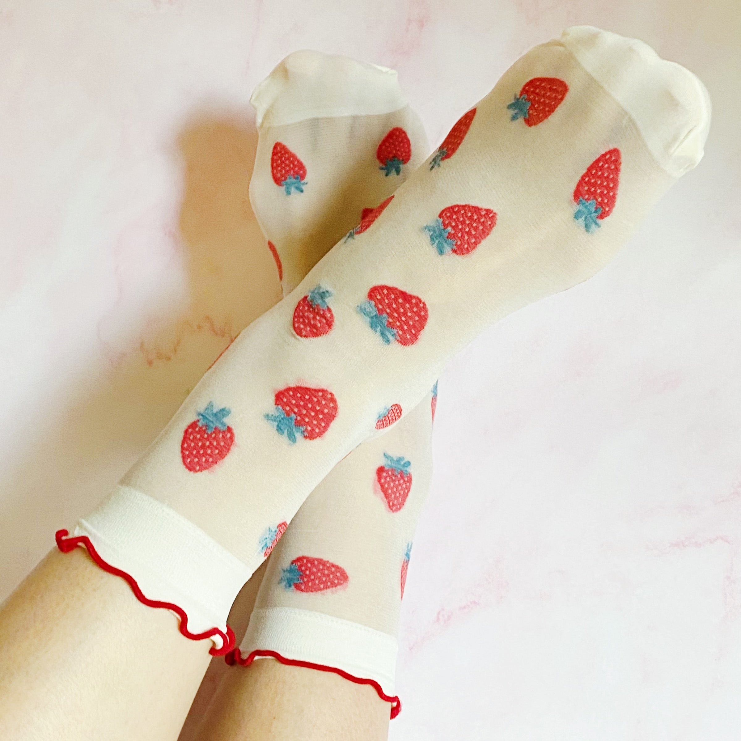 A set of two pairs of sheer socks featuring playful dots and strawberries, showcasing their soft and stretchy material.