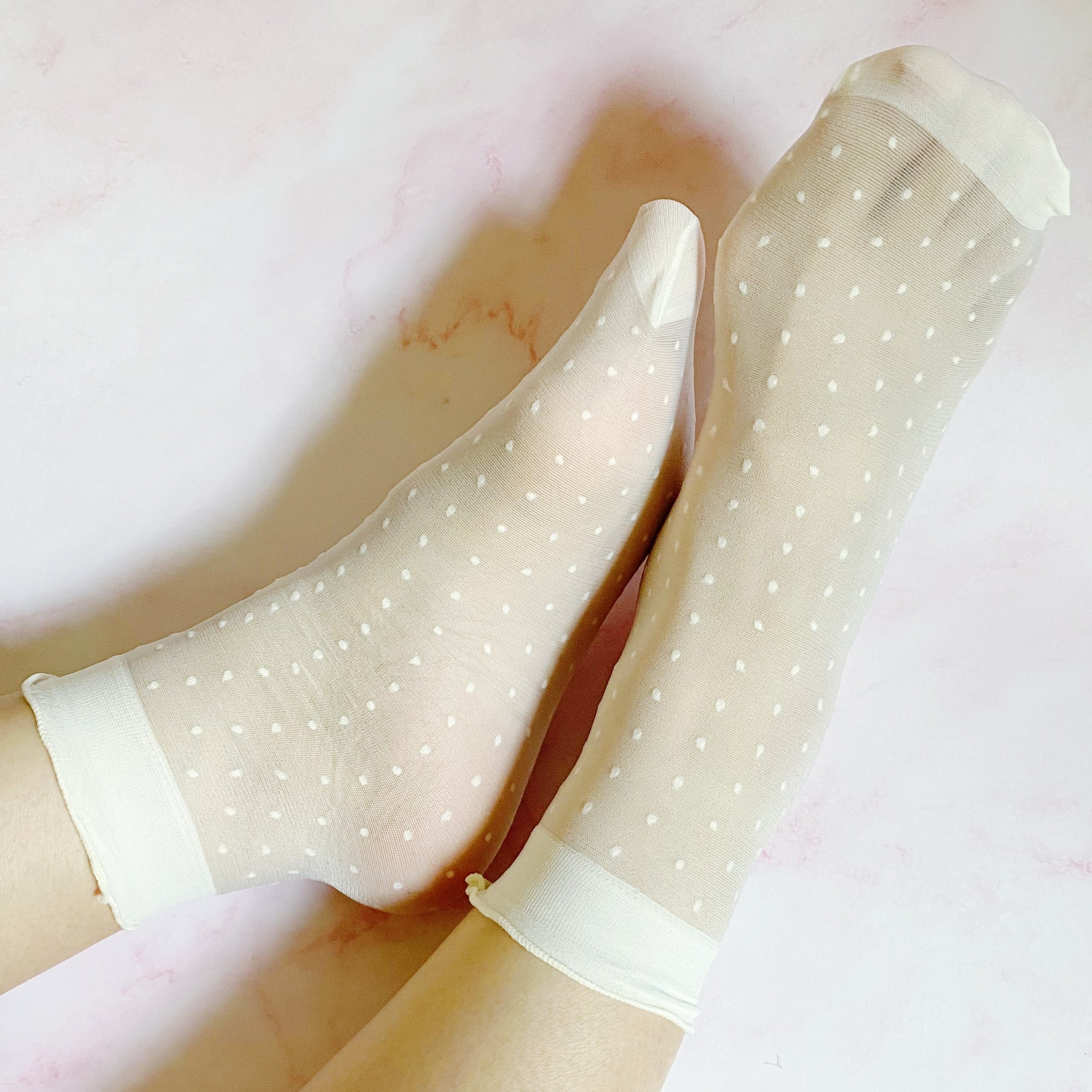 A set of two pairs of sheer socks featuring playful dots and strawberries, showcasing their soft and stretchy material.