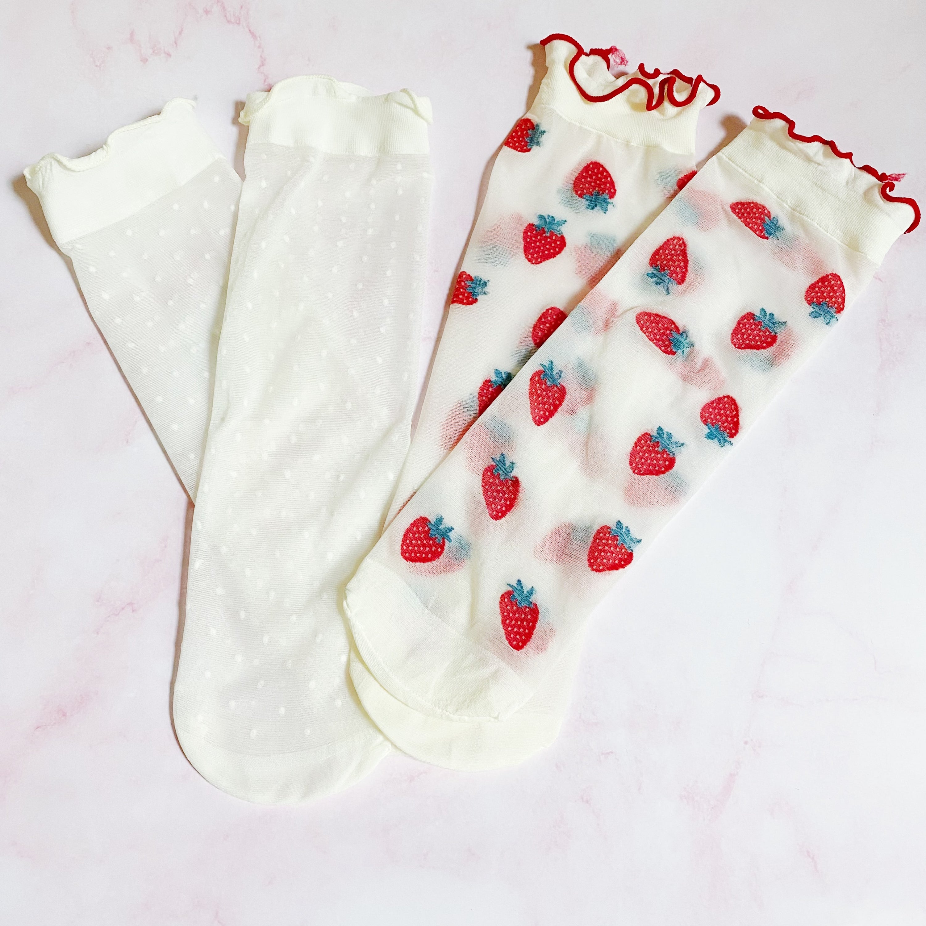 A set of two pairs of sheer socks featuring playful dots and strawberries, showcasing their soft and stretchy material.