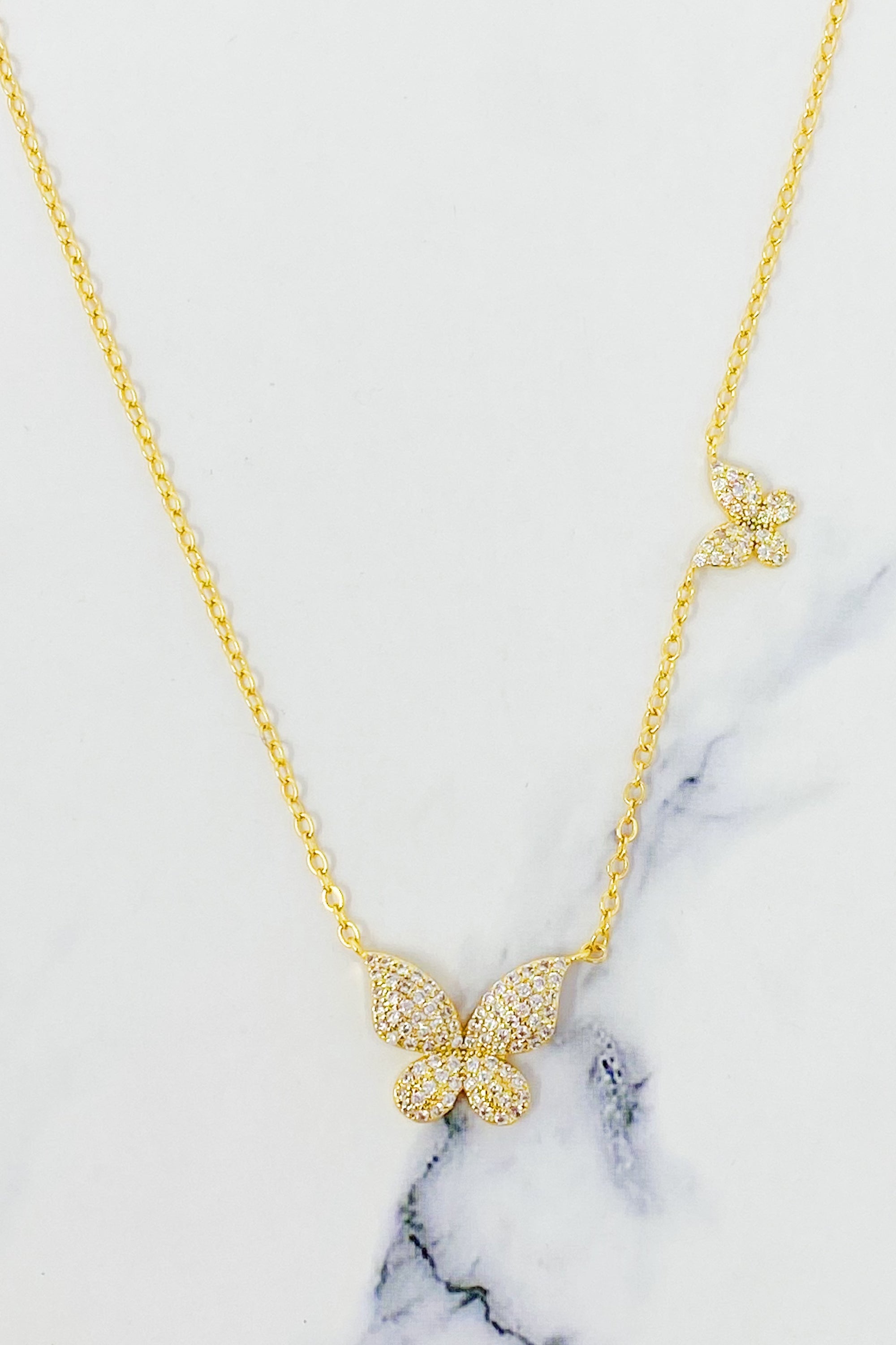 Double Shine Butterfly Necklace featuring two sparkling butterfly pendants on a gold tone chain.