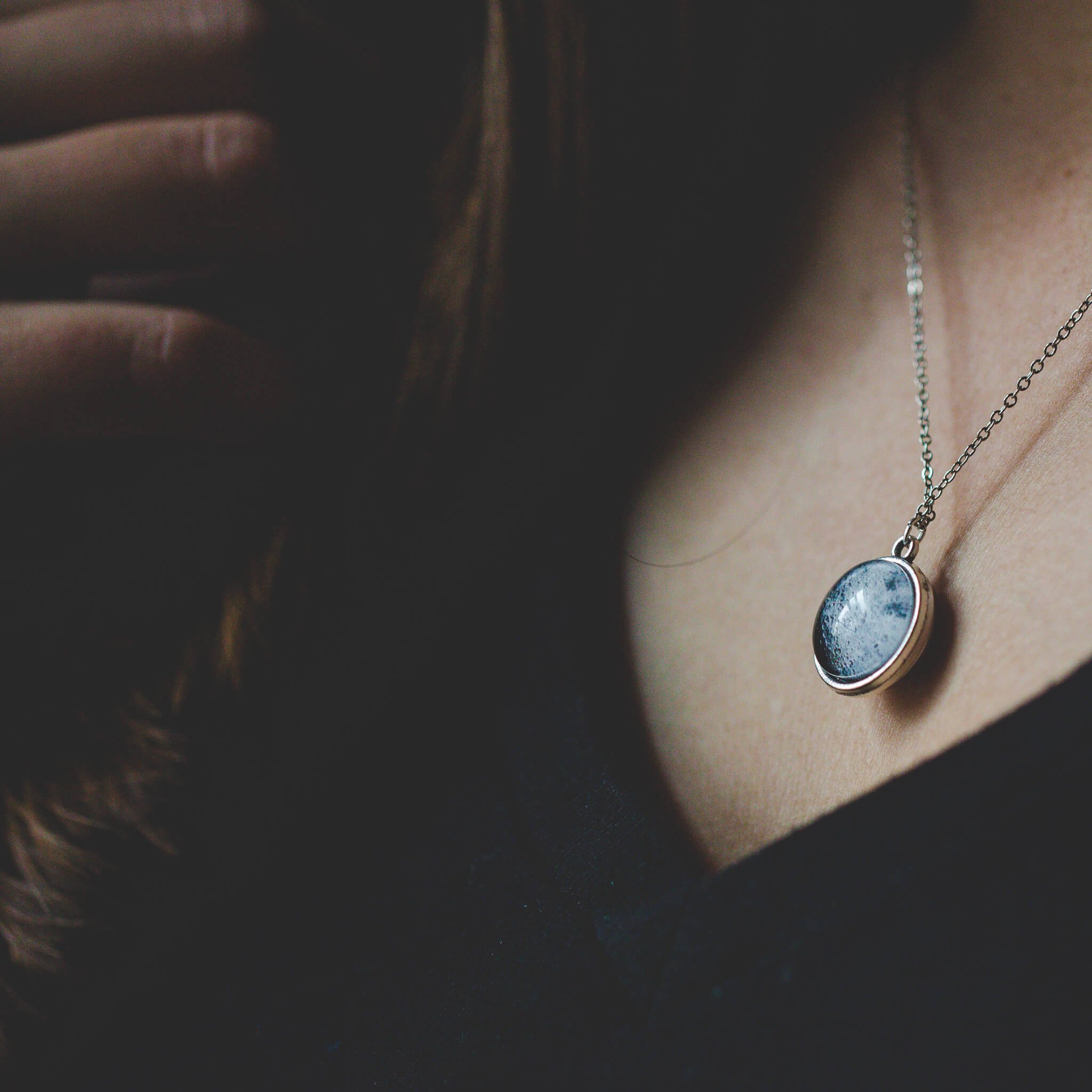 Double Sided Moon Necklace featuring the moon's face and dark side, available in antique bronze and silver tones.