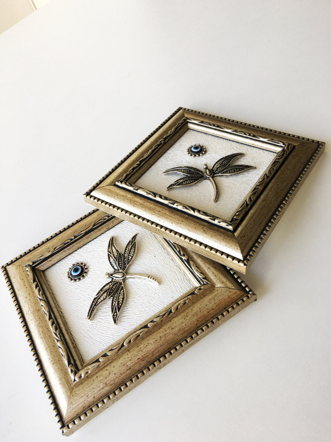 Handmade Dragonfly Framed Wall Decor featuring a silver dragonfly and a small evil eye bead, perfect for home decoration.