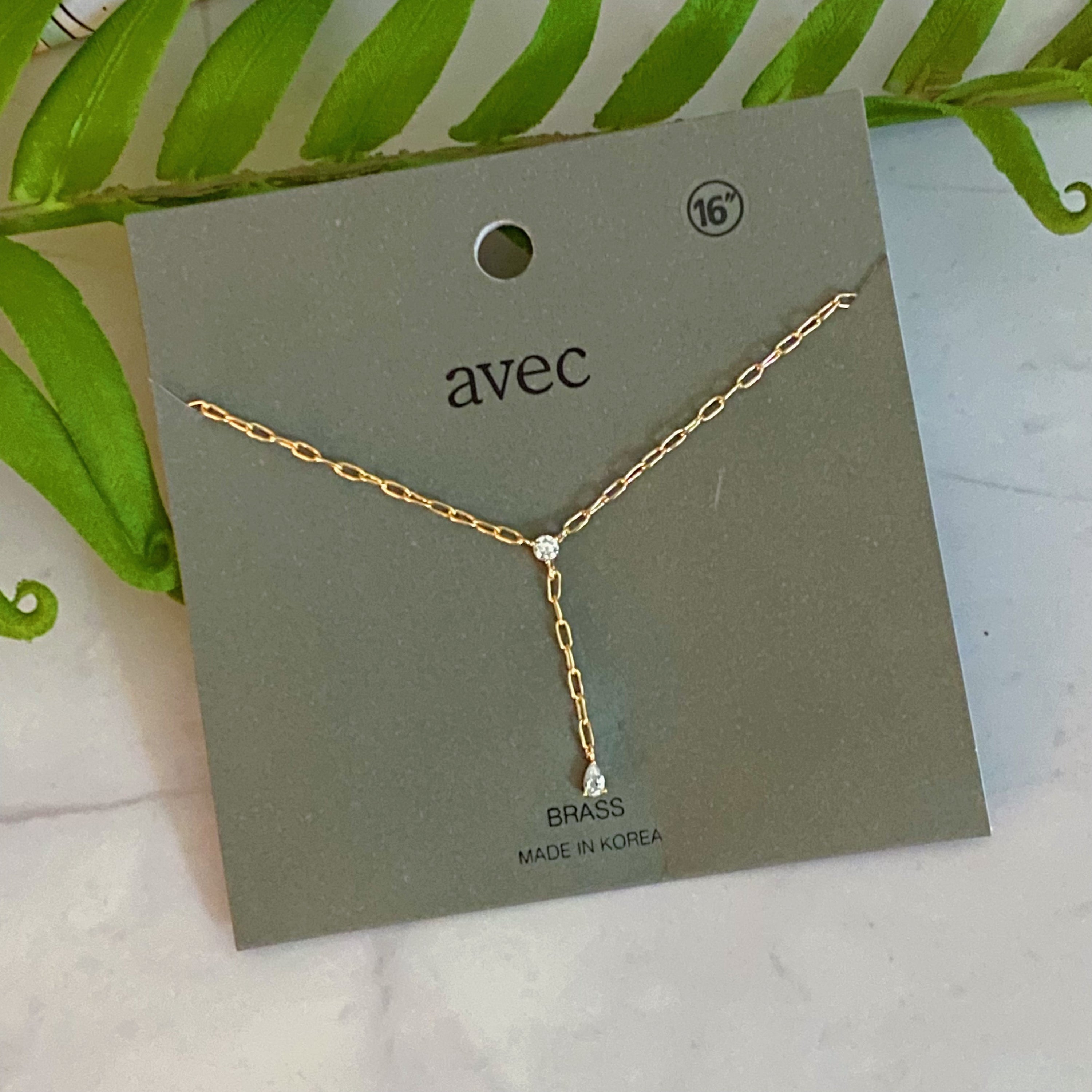 A delicate gold plated brass necklace featuring a T drop design with sparkling cubic zirconia stones, elegantly displayed on a soft background.