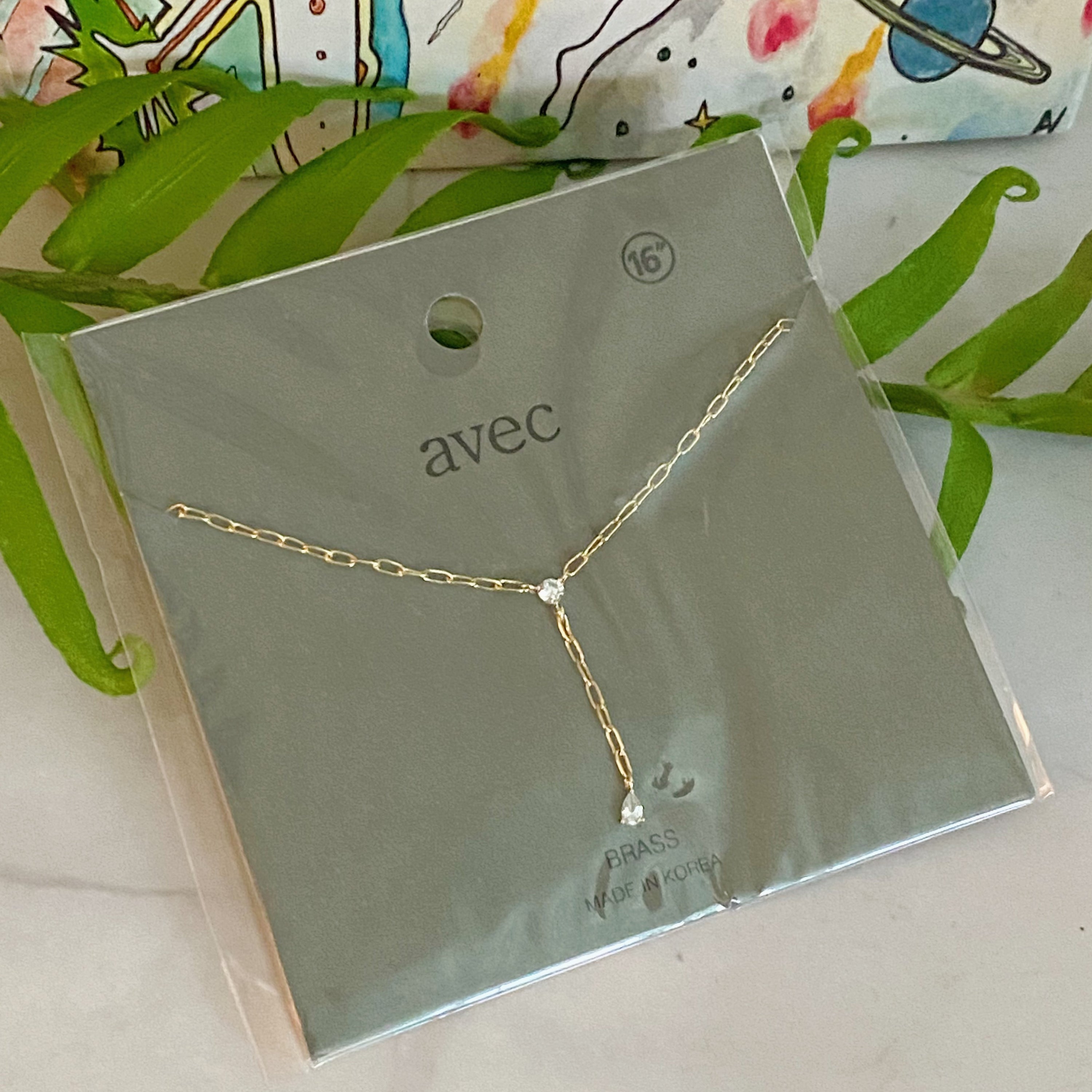 A delicate gold plated brass necklace featuring a T drop design with sparkling cubic zirconia stones, elegantly displayed on a soft background.