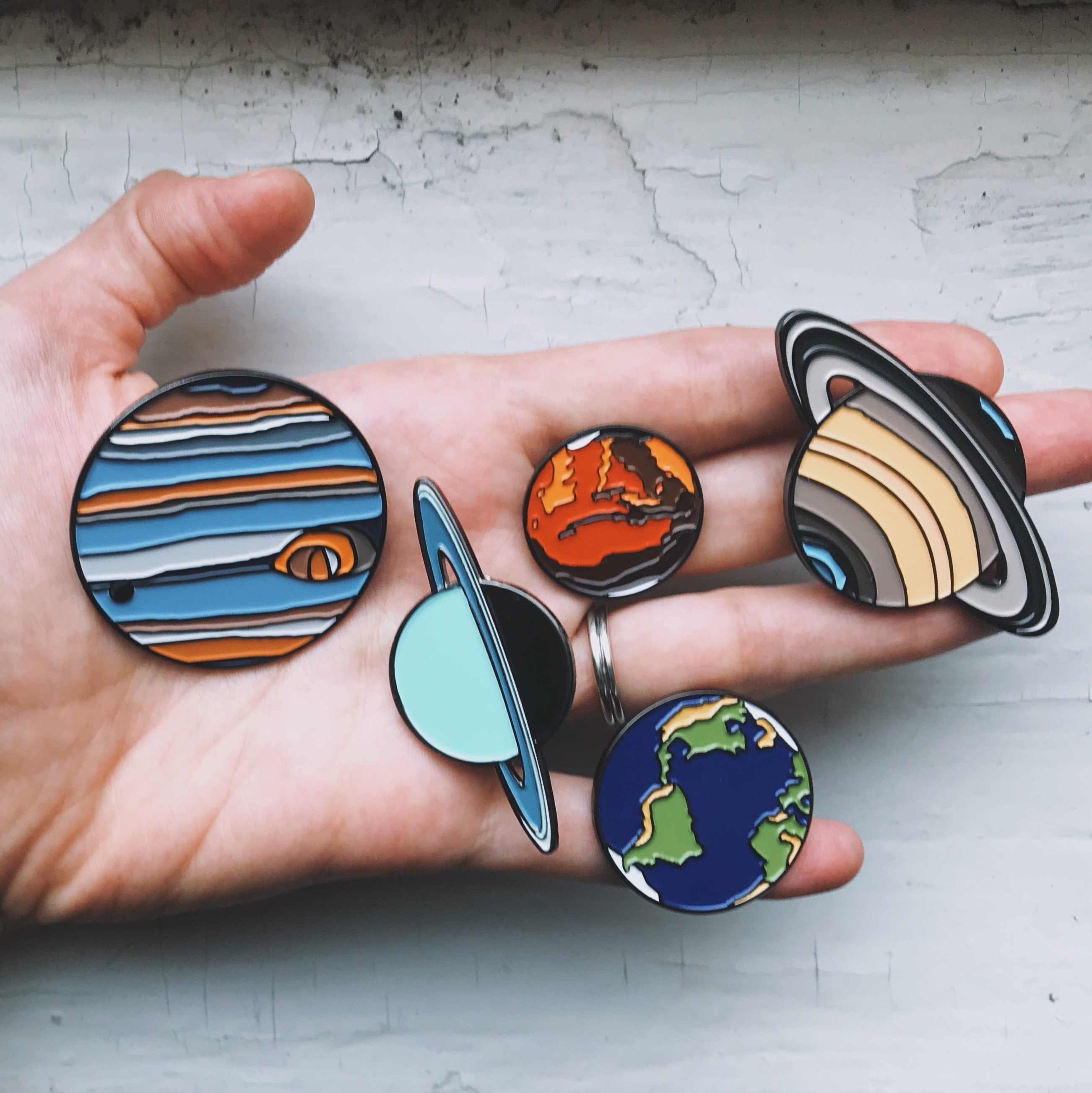 A colorful Earth Enamel Pin featuring a vibrant blue planet design, perfect for jackets and backpacks.