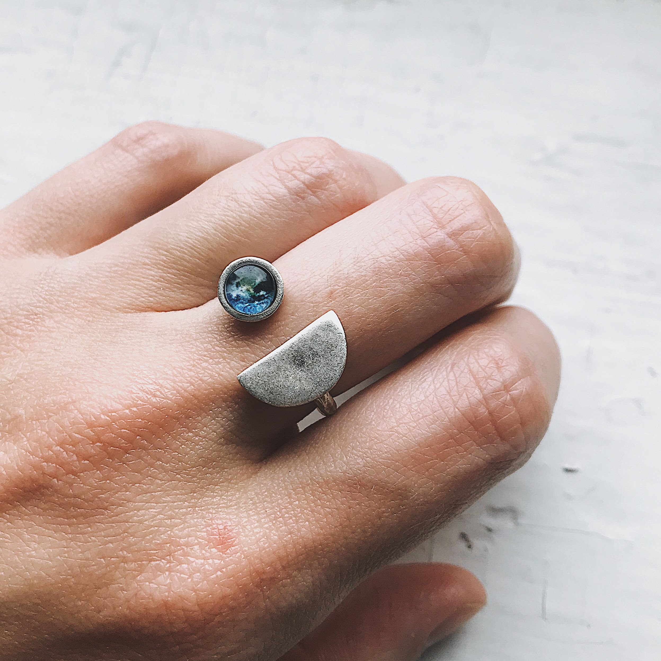 Earth Rise Ring featuring a glass image of Earth from the Moon, handcrafted in rhodium plated brass, available in silver and gold tones.