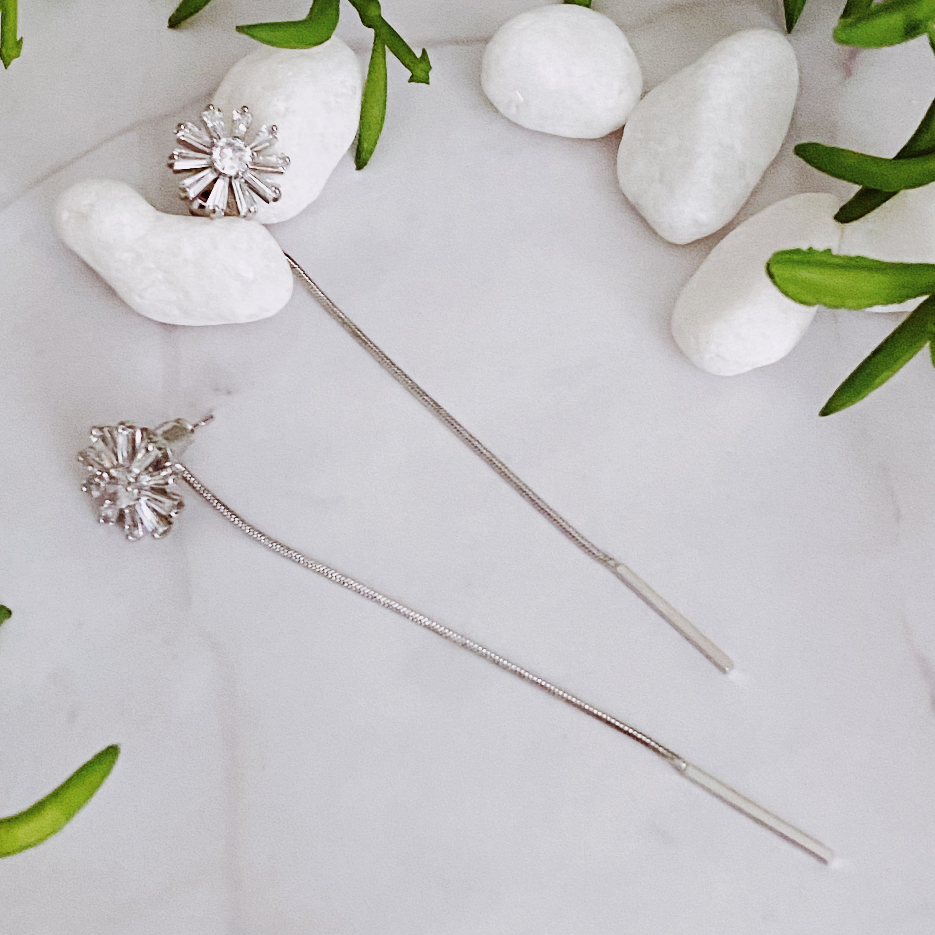 Edelweiss Backdrop Earrings featuring a sparkly flower stud and chain dangle, elegantly displayed on a soft background.