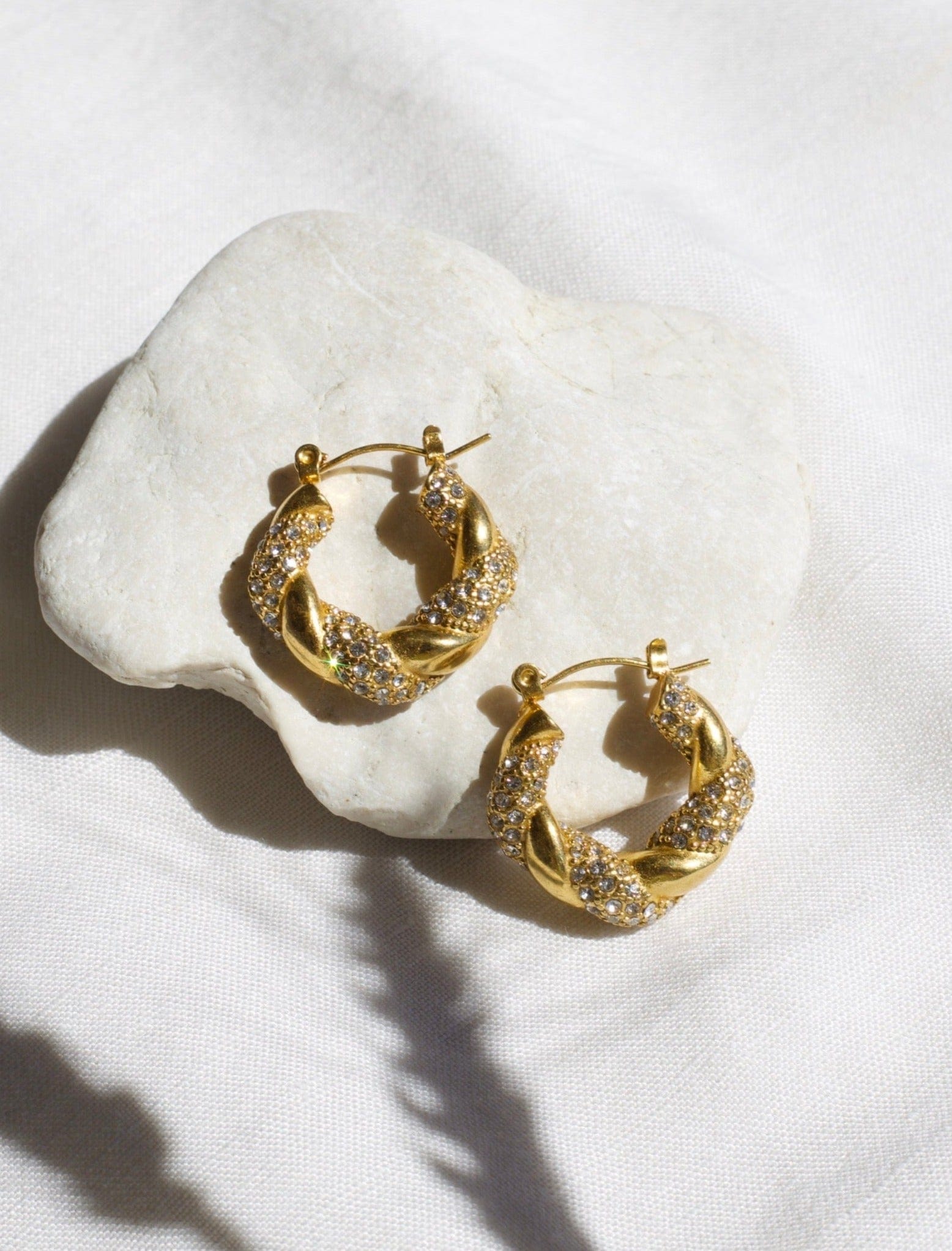 Elegant Egypt twist hoop earrings made of stainless steel with 18K gold PVD plating and zircon crystal pavé, showcasing a unique twist design.