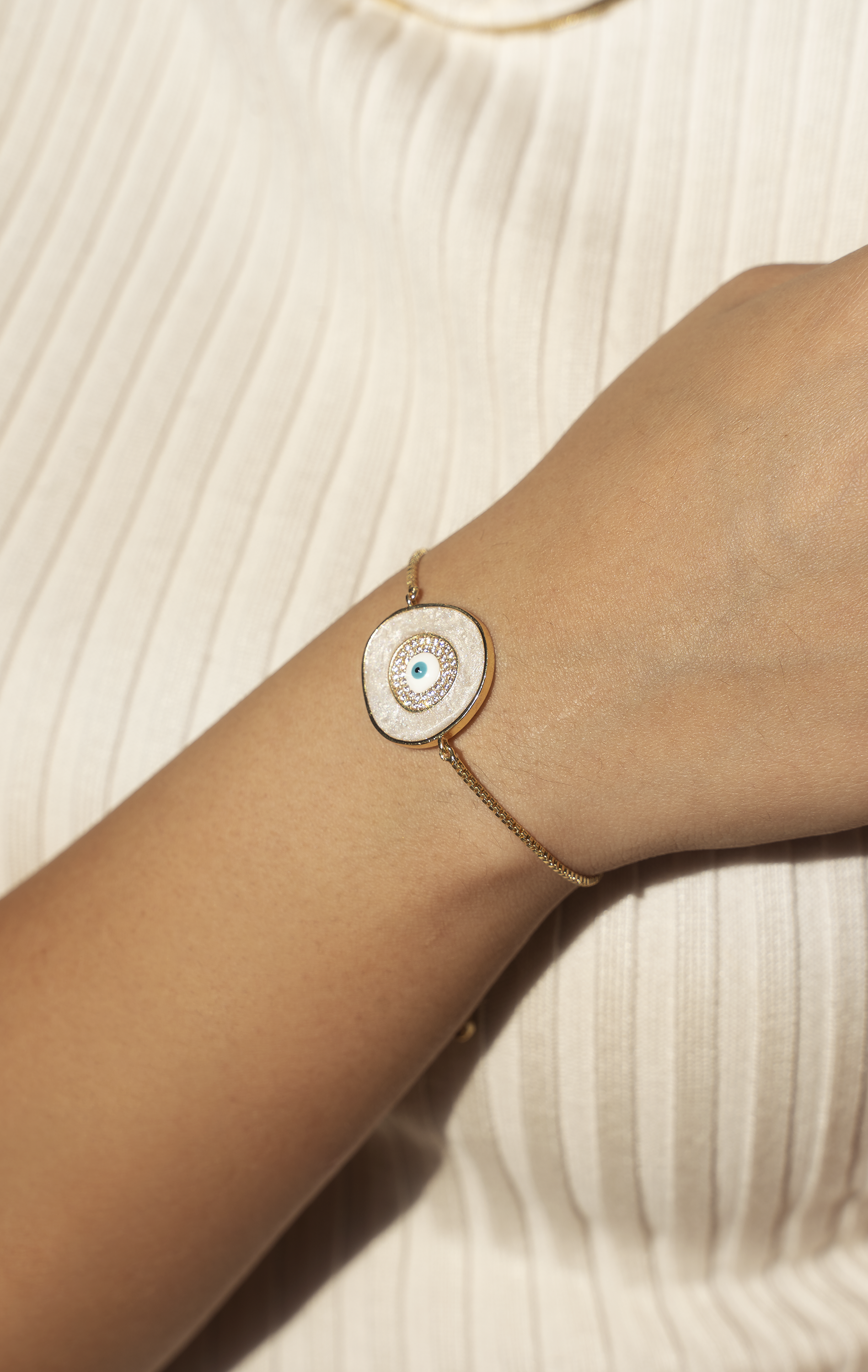 A beautiful ELA Bracelet featuring a baby blue enamel evil eye charm, adjustable bolo design, and yellow gold plating.