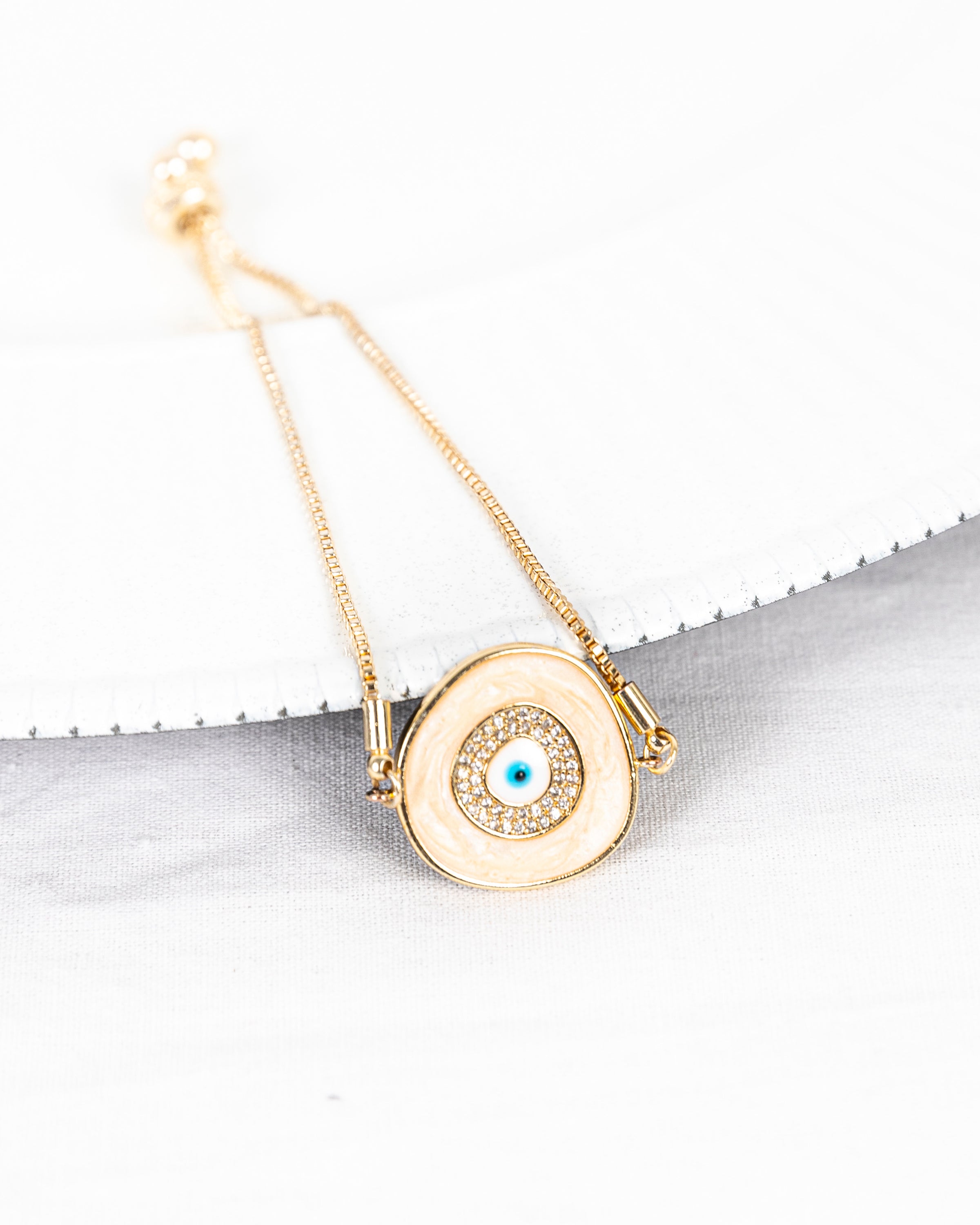 A beautiful ELA Bracelet featuring a baby blue enamel evil eye charm, adjustable bolo design, and yellow gold plating.