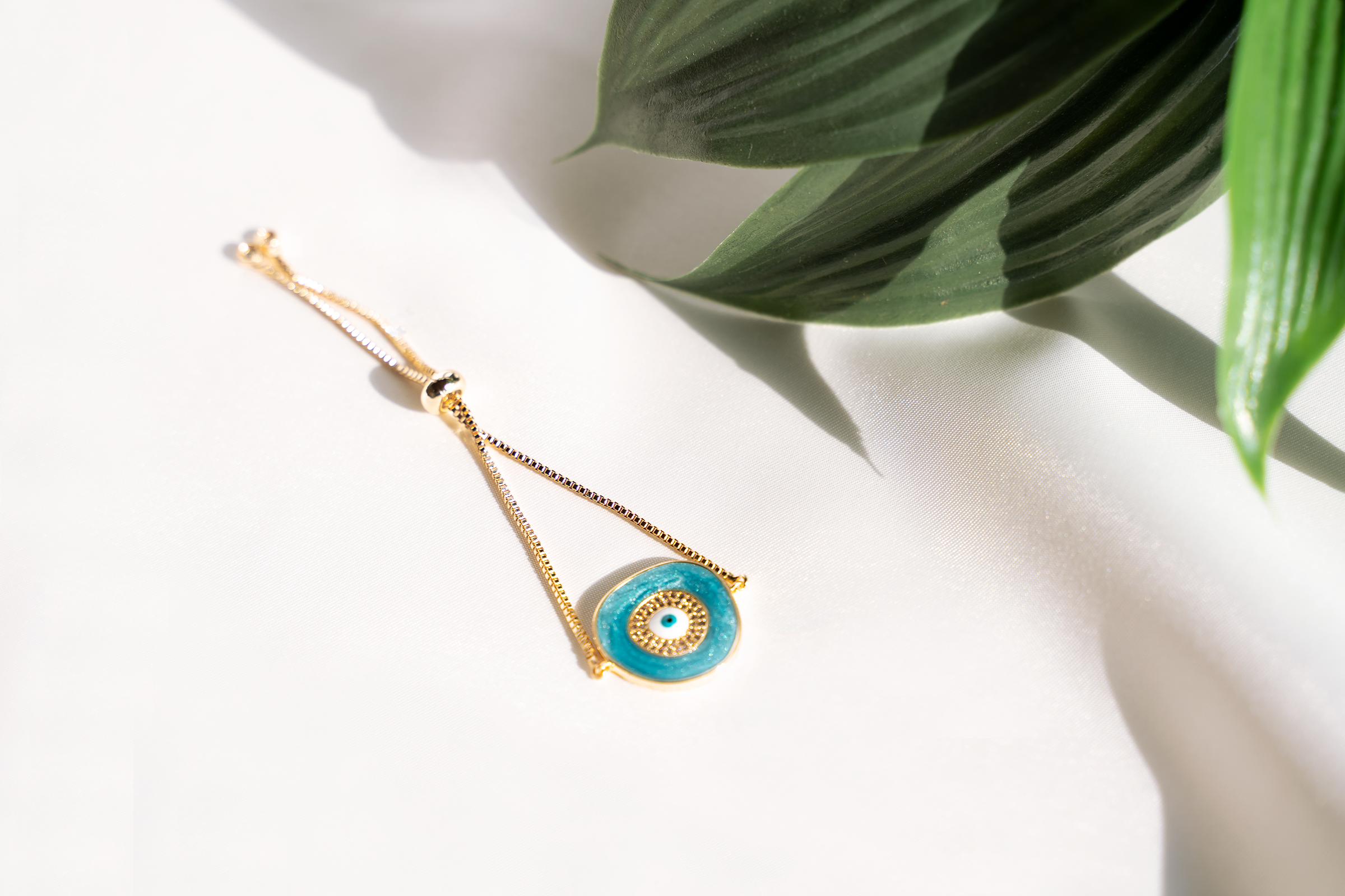 A beautiful ELA Bracelet featuring a baby blue enamel evil eye charm, adjustable bolo design, and yellow gold plating.