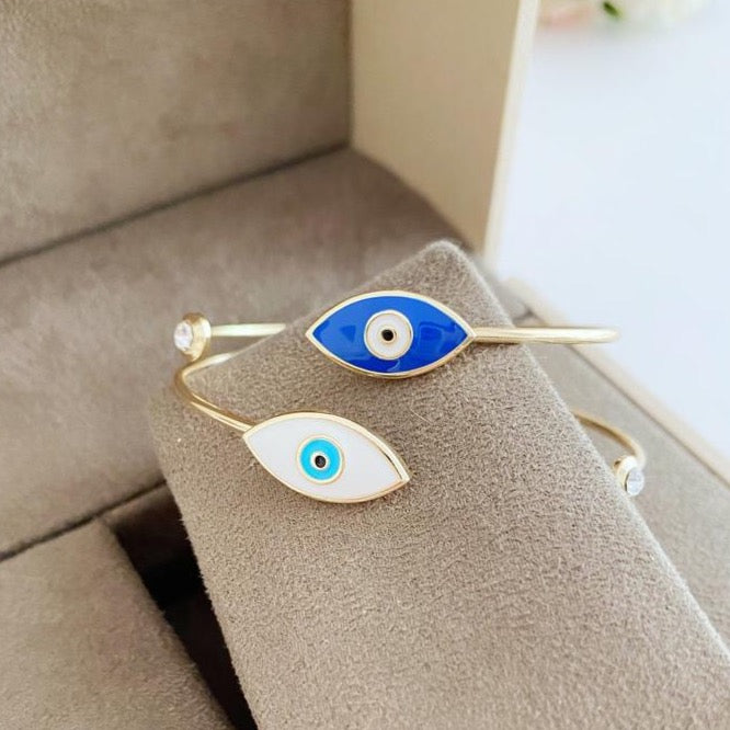 Elegant gold cuff bracelet featuring a movable evil eye charm, showcasing intricate design and customizable colors.